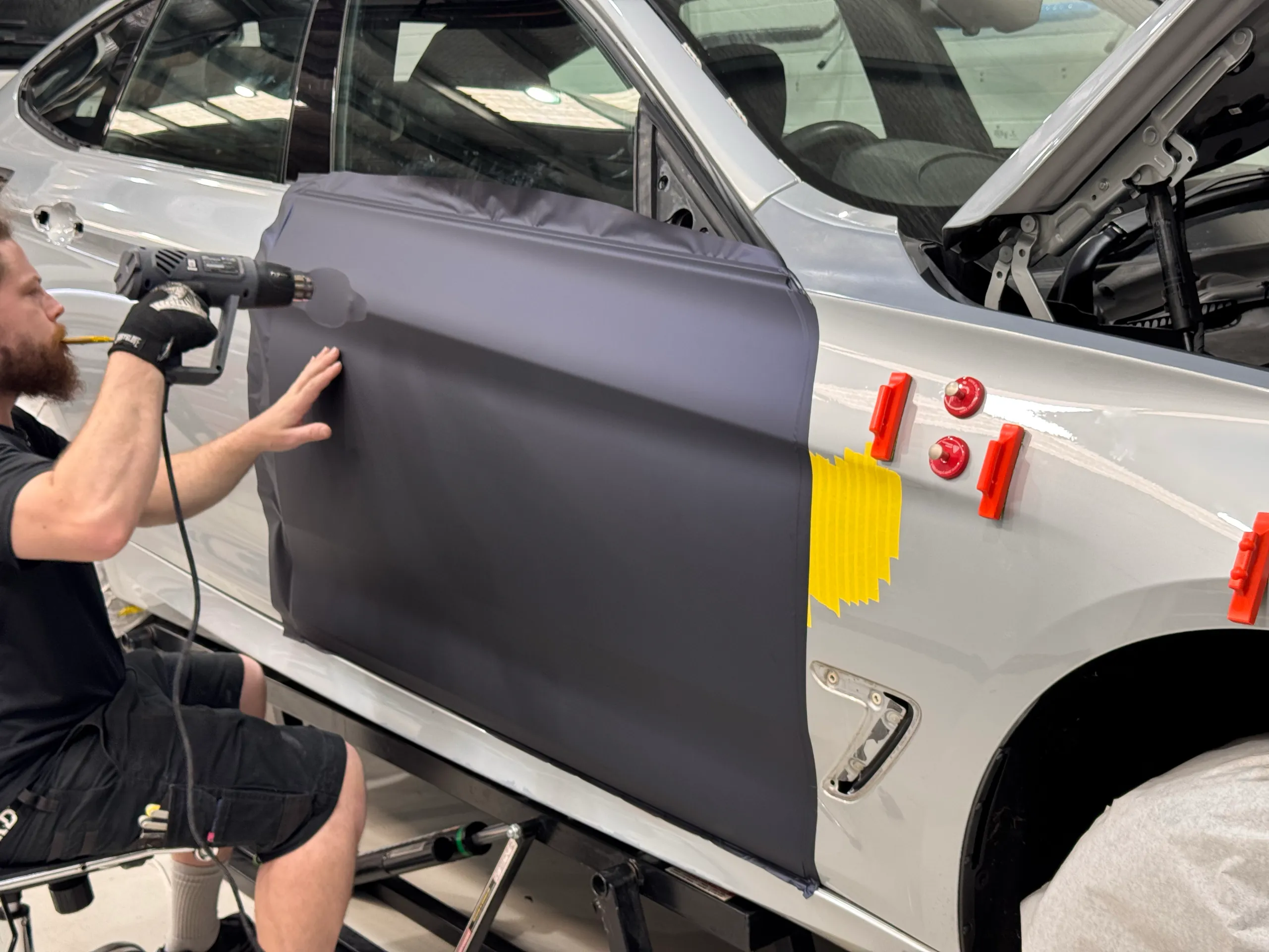 Installer heating blue-grey film on the BMW Gran Turismo door during a colour change