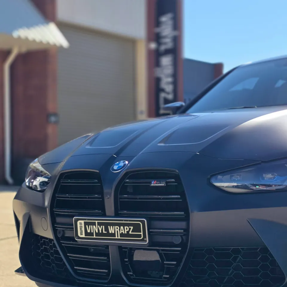Front grille and headlight of a satin grey BMW M3 Competition outdoors