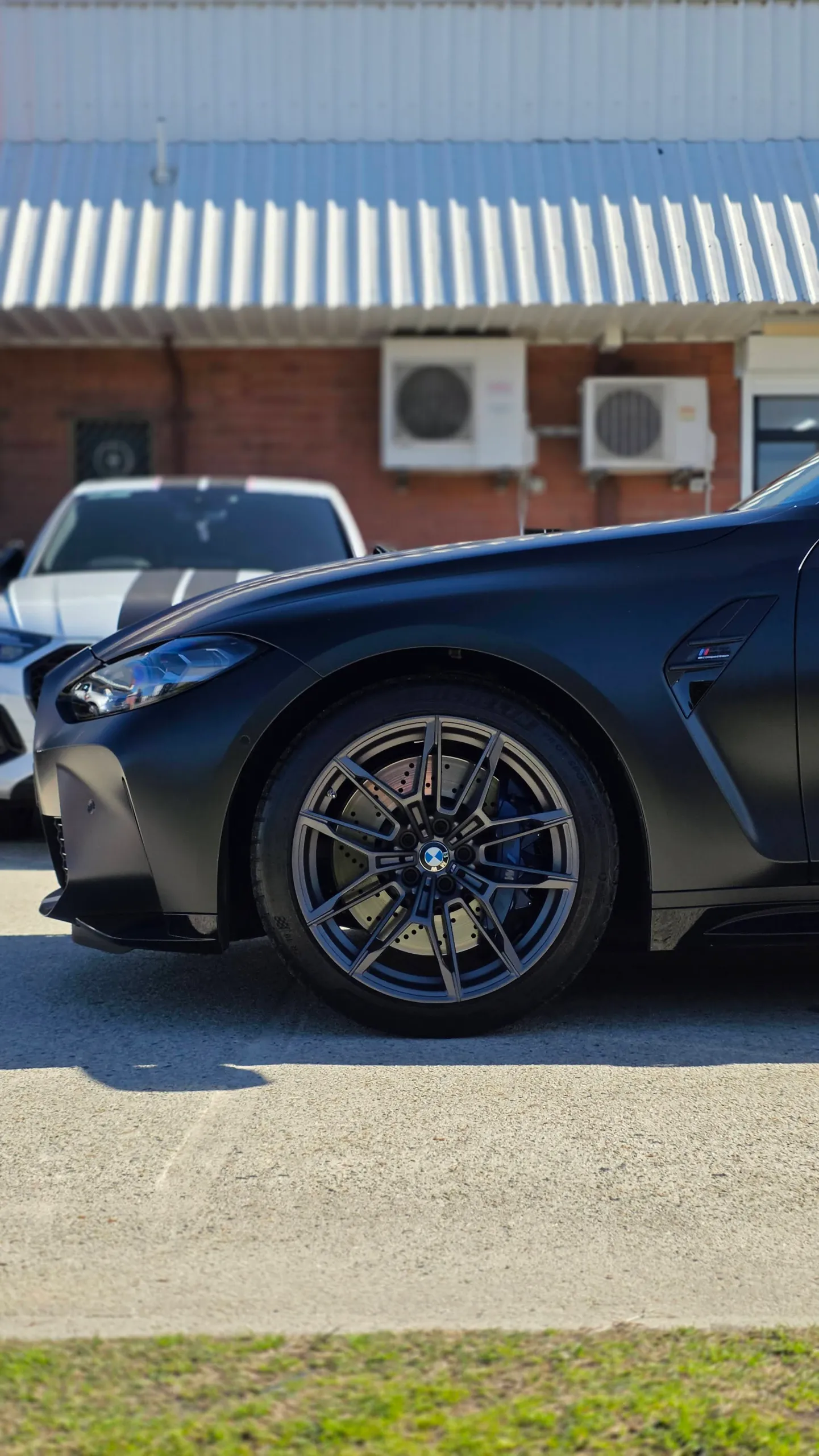 BMW M3 Competition front wheel and satin grey guard outside the workshop
