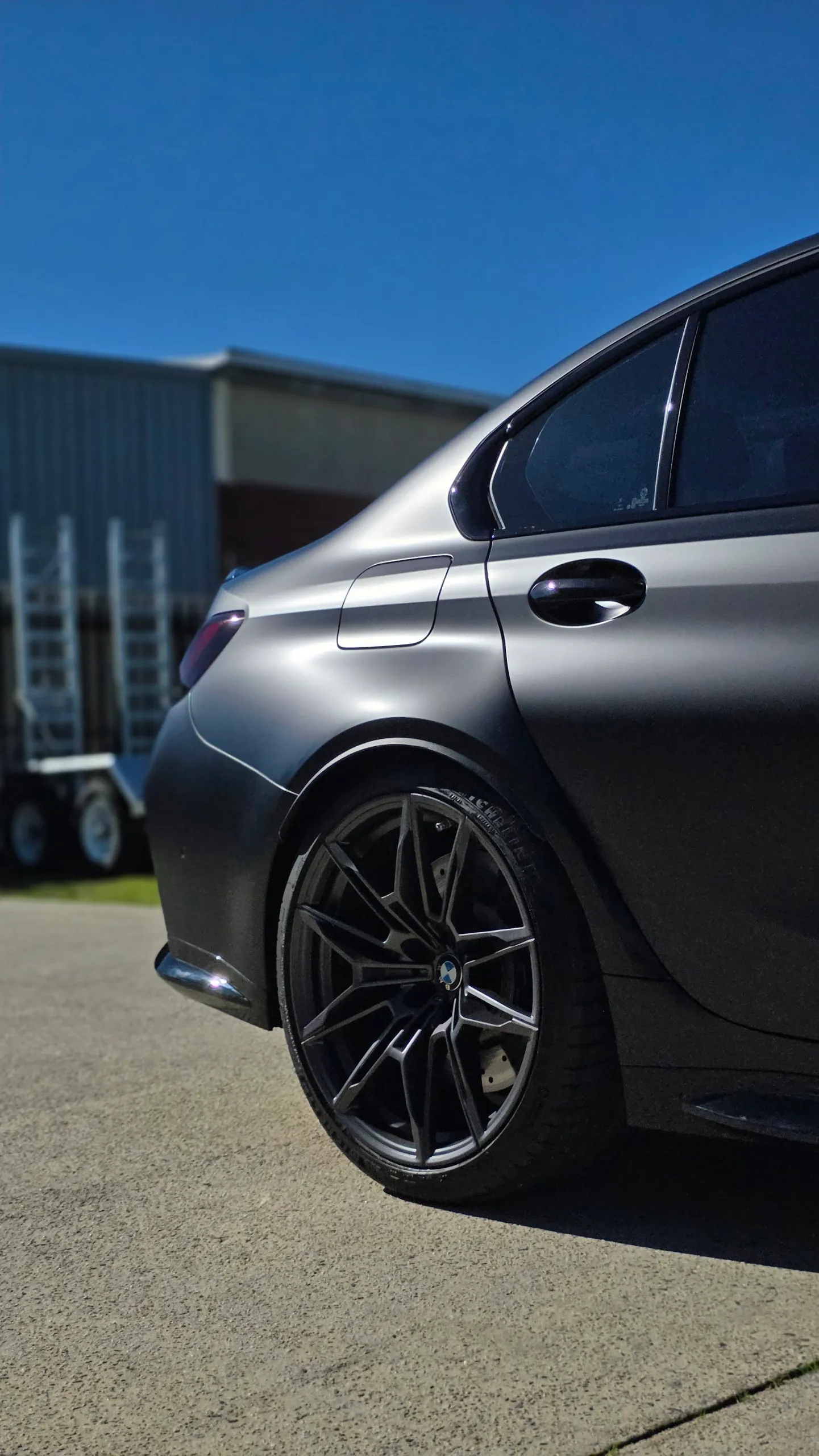 Rear door, quarter panel and wheel of a satin grey BMW M3 Competition outdoors