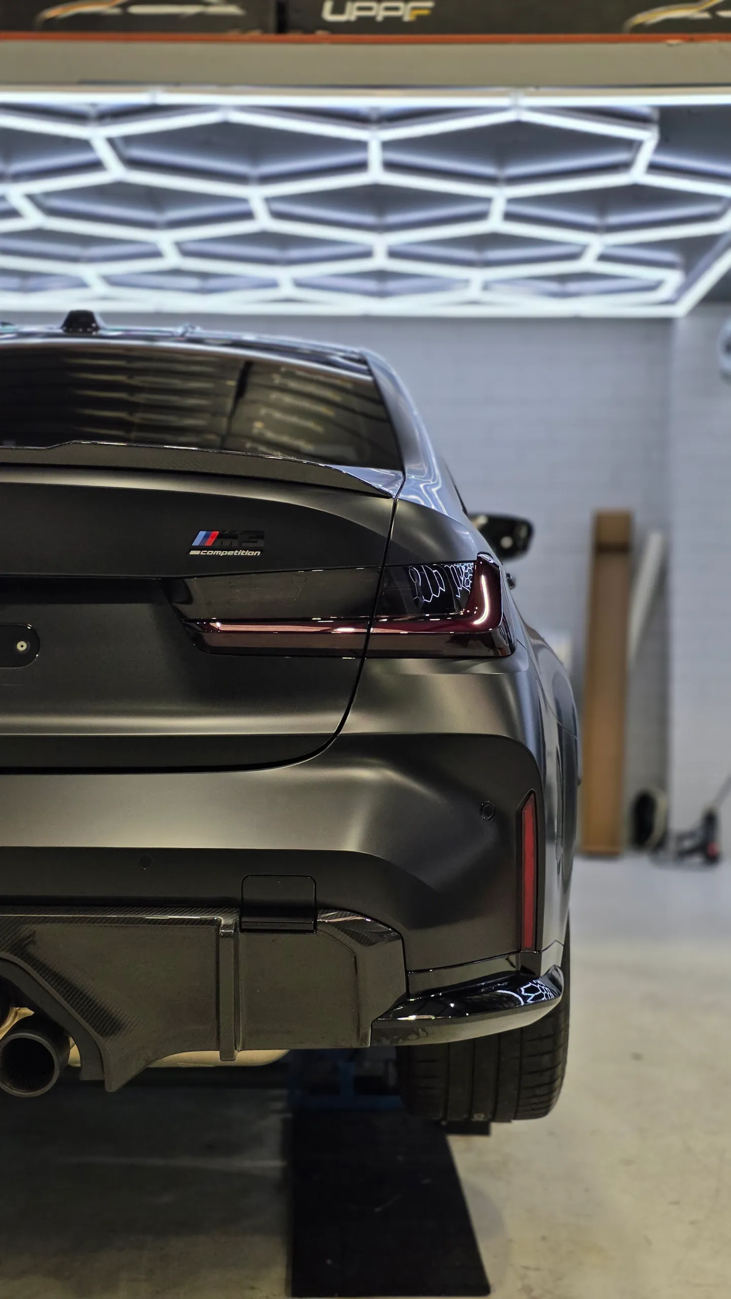 Rear lights, boot and diffuser of a satin grey BMW M3 Competition in the workshop