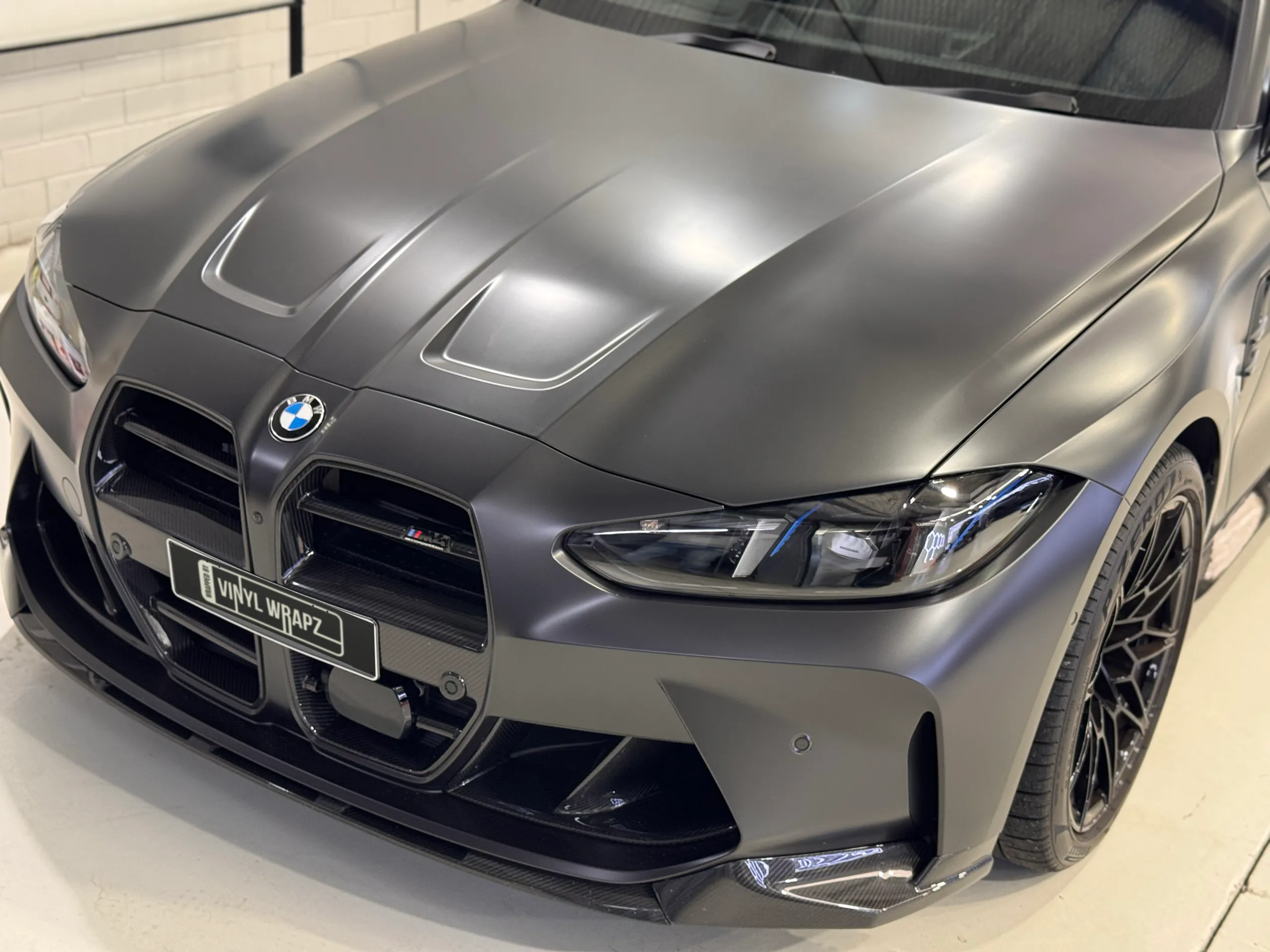 Elevated view of the satin dark grey BMW M4 Competition bonnet, grille and front bumper
