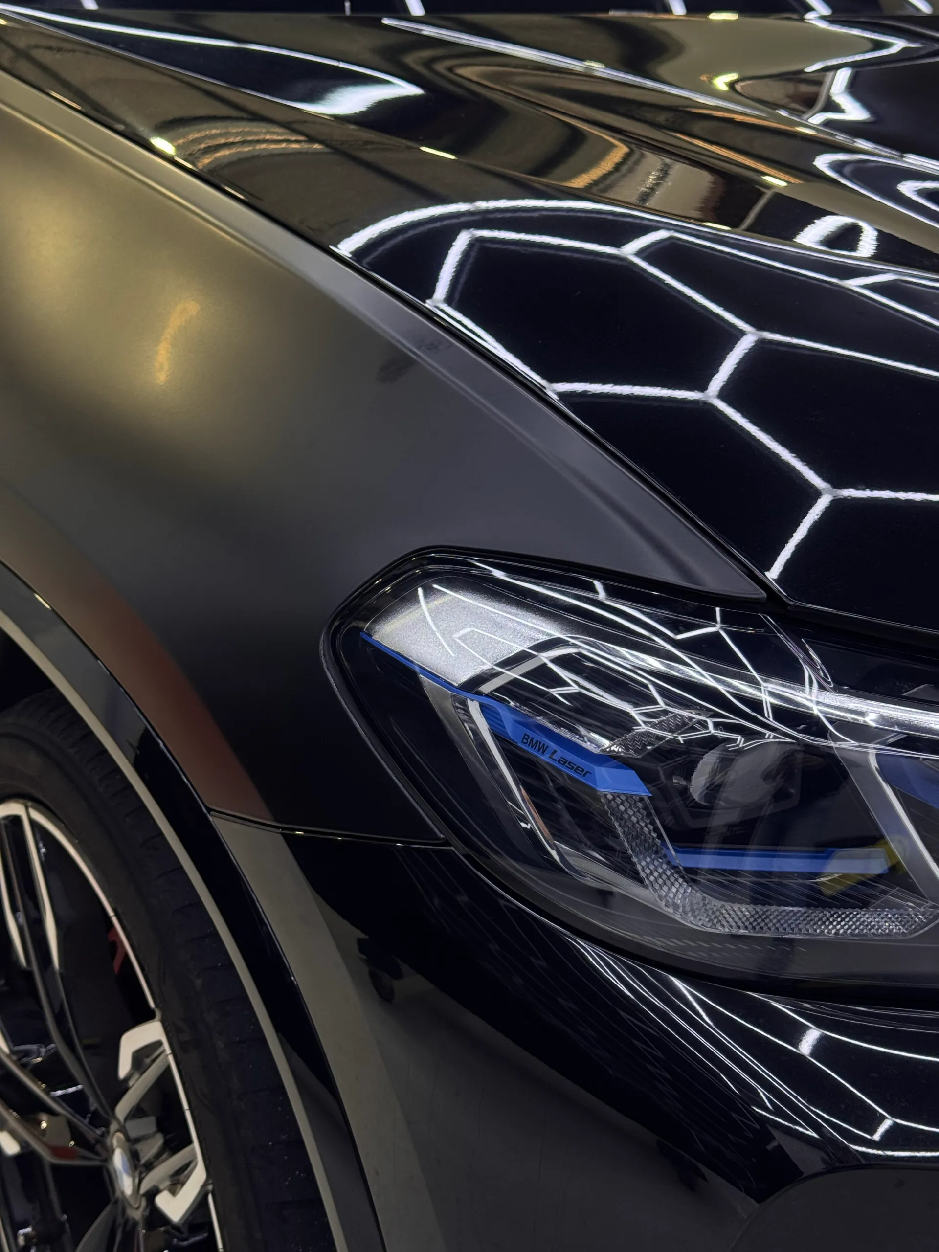 BMW X3 M40i headlight beside a matte dark grey front guard and glossy bonnet during film work