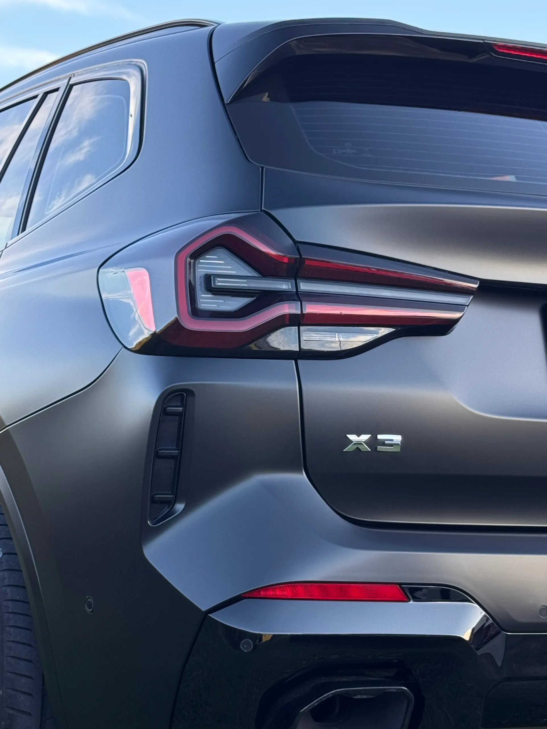 BMW X3 badge beside the rear light on a matte dark grey tailgate