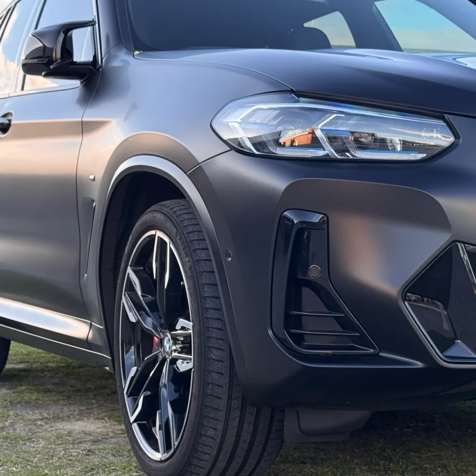 Matte dark grey BMW X3 M40i front quarter and side parked on grass