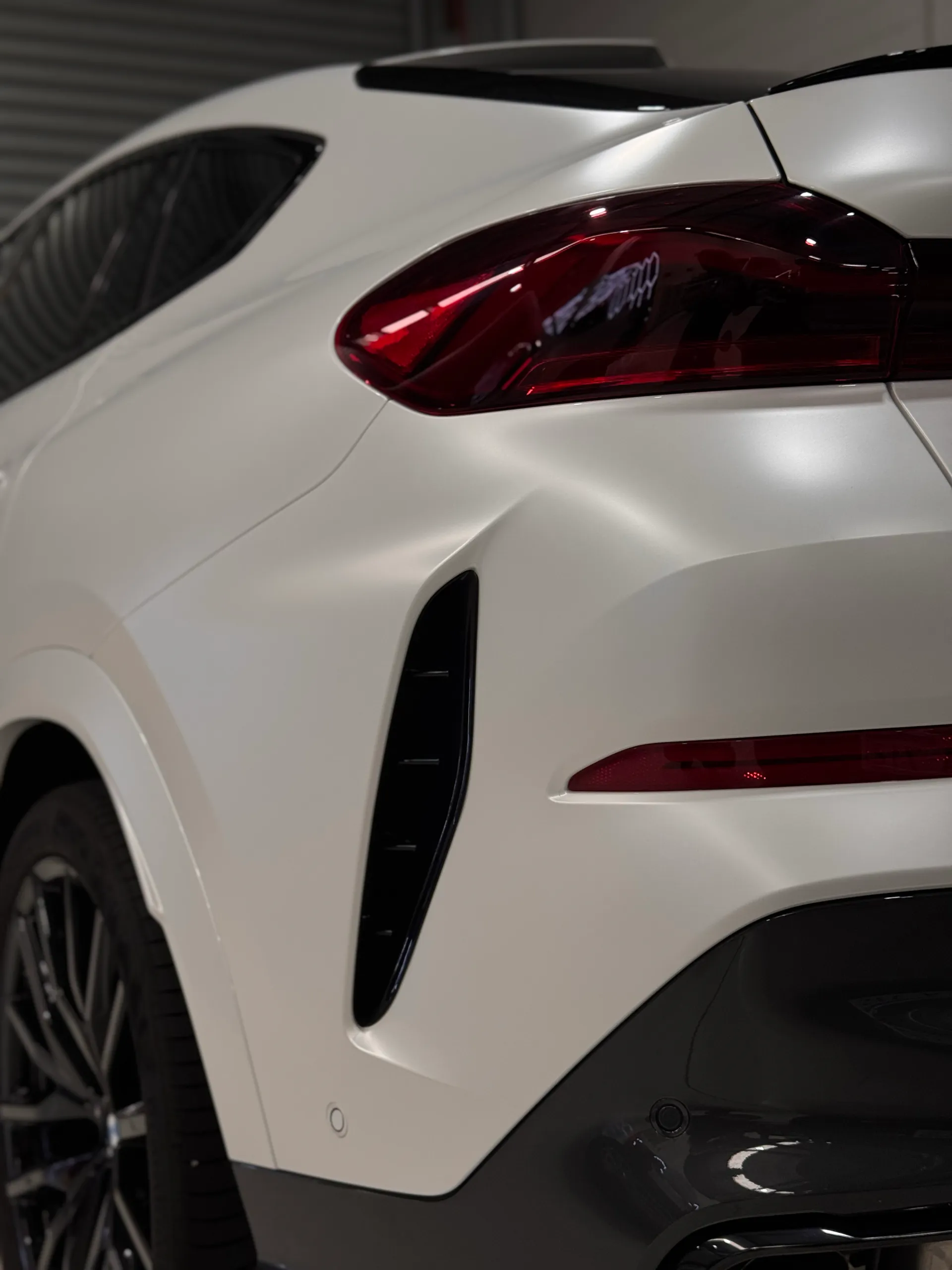 Satin white BMW X6 rear quarter and black lower bumper trim