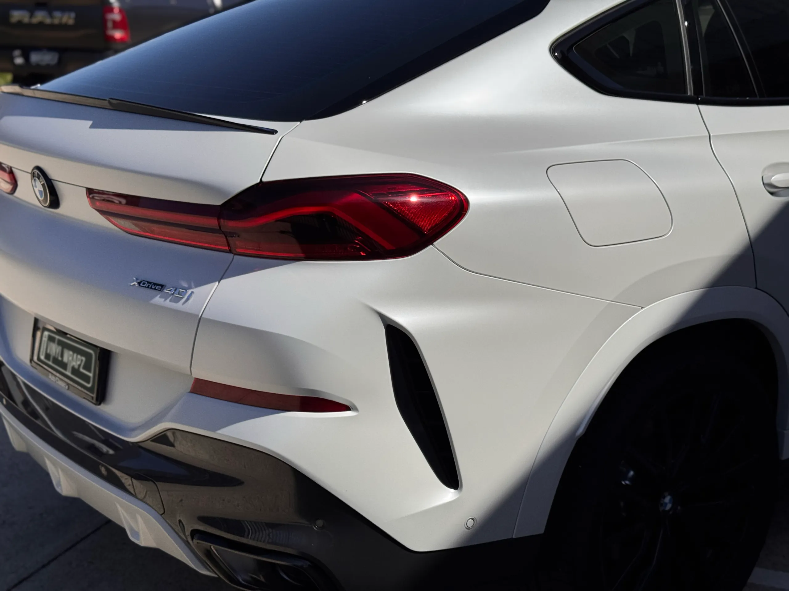 Satin white BMW X6 tailgate and rear quarter in sunlight