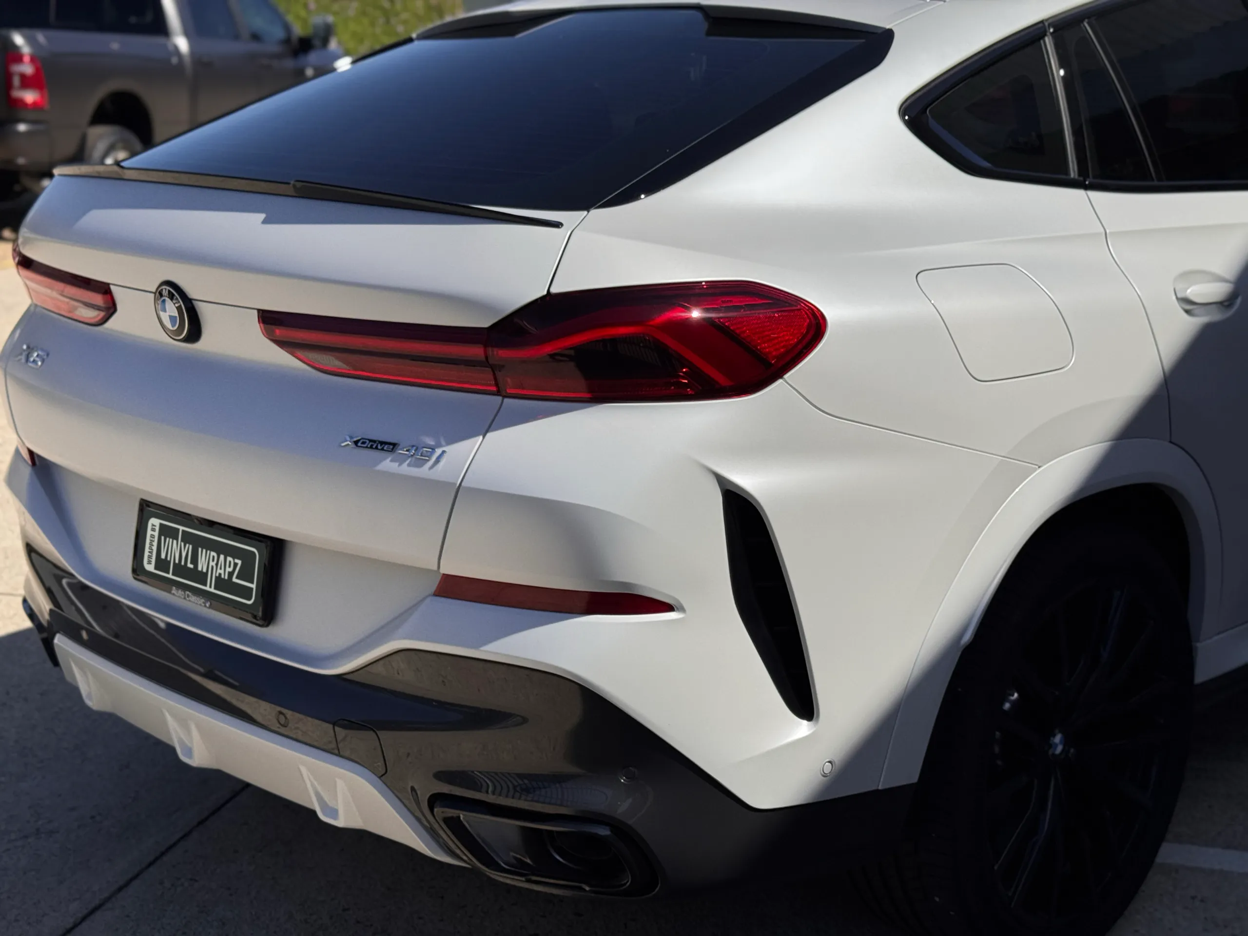 BMW X6 rear quarter with satin white bodywork and gloss black bumper trim outdoors