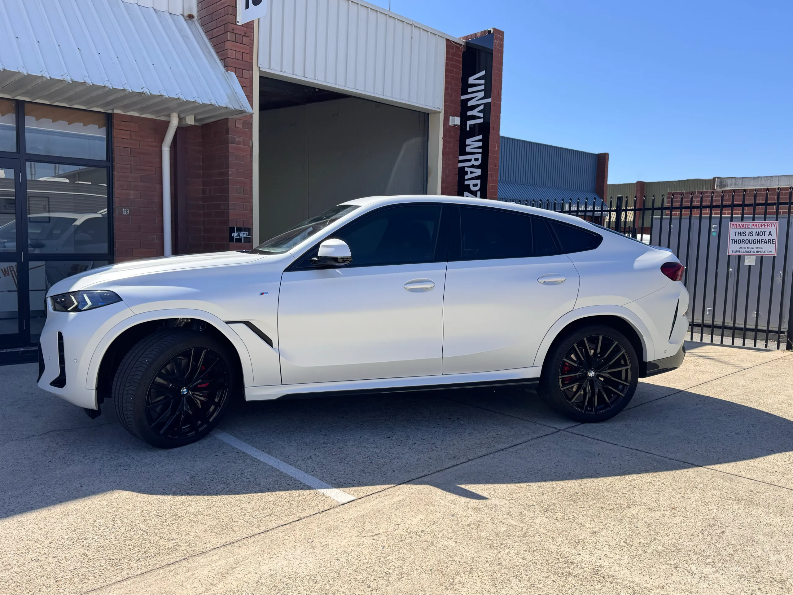 Satin white BMW X6 with black wheels outside the Vinyl Wrapz workshop