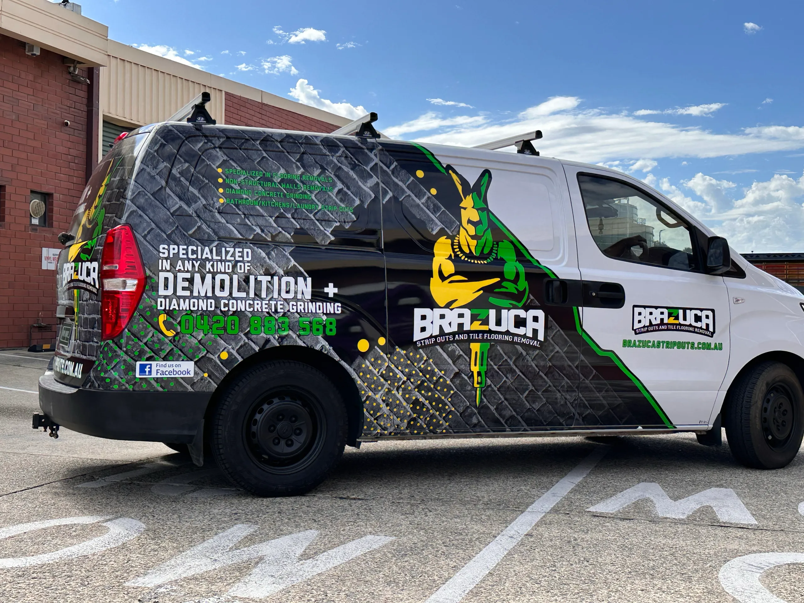 Brazuca Hyundai iLoad with black brick graphics and a green and yellow kangaroo design outdoors