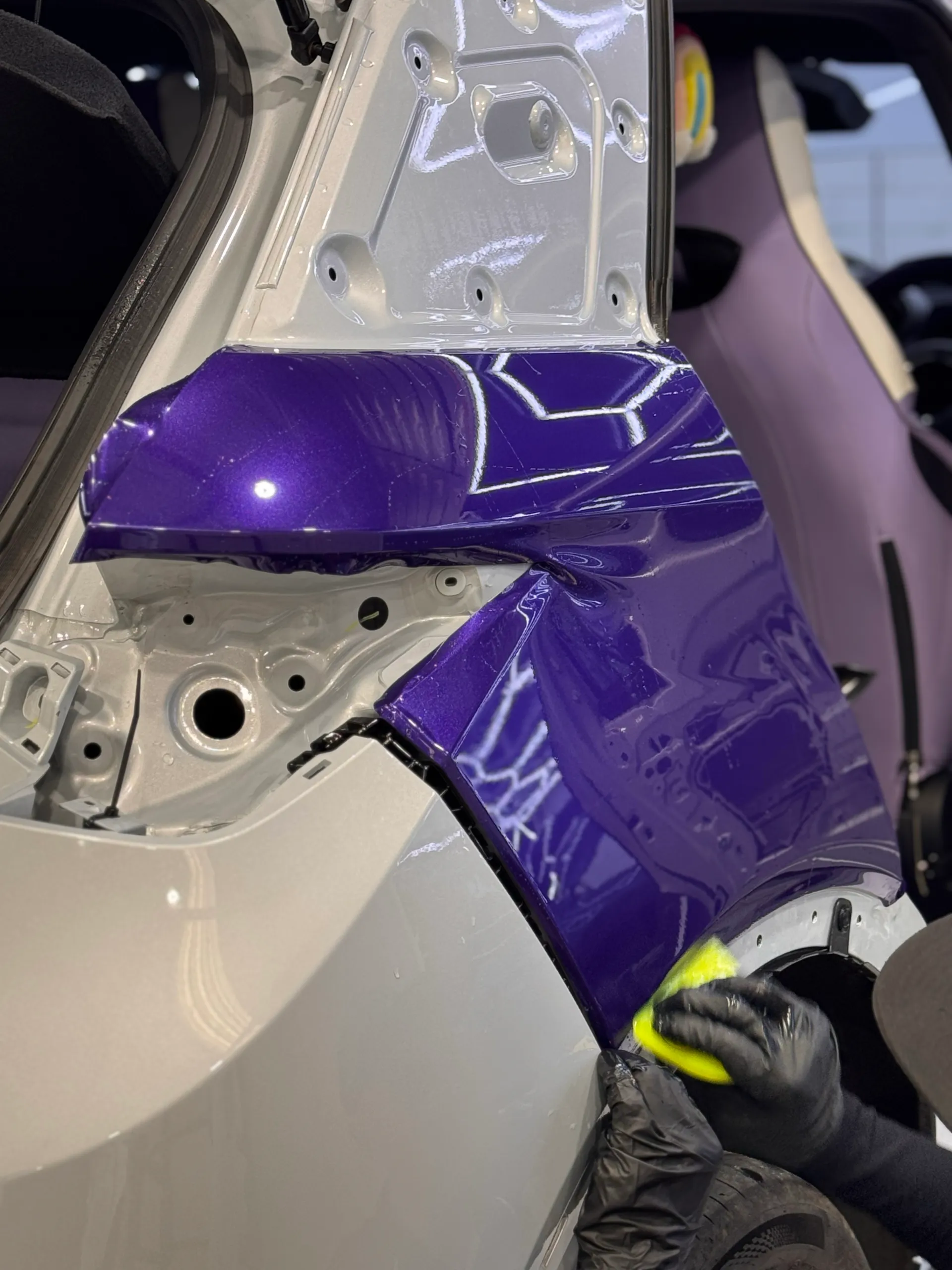 Gloved hands fitting purple film around the BYD Atto 3 rear-light opening