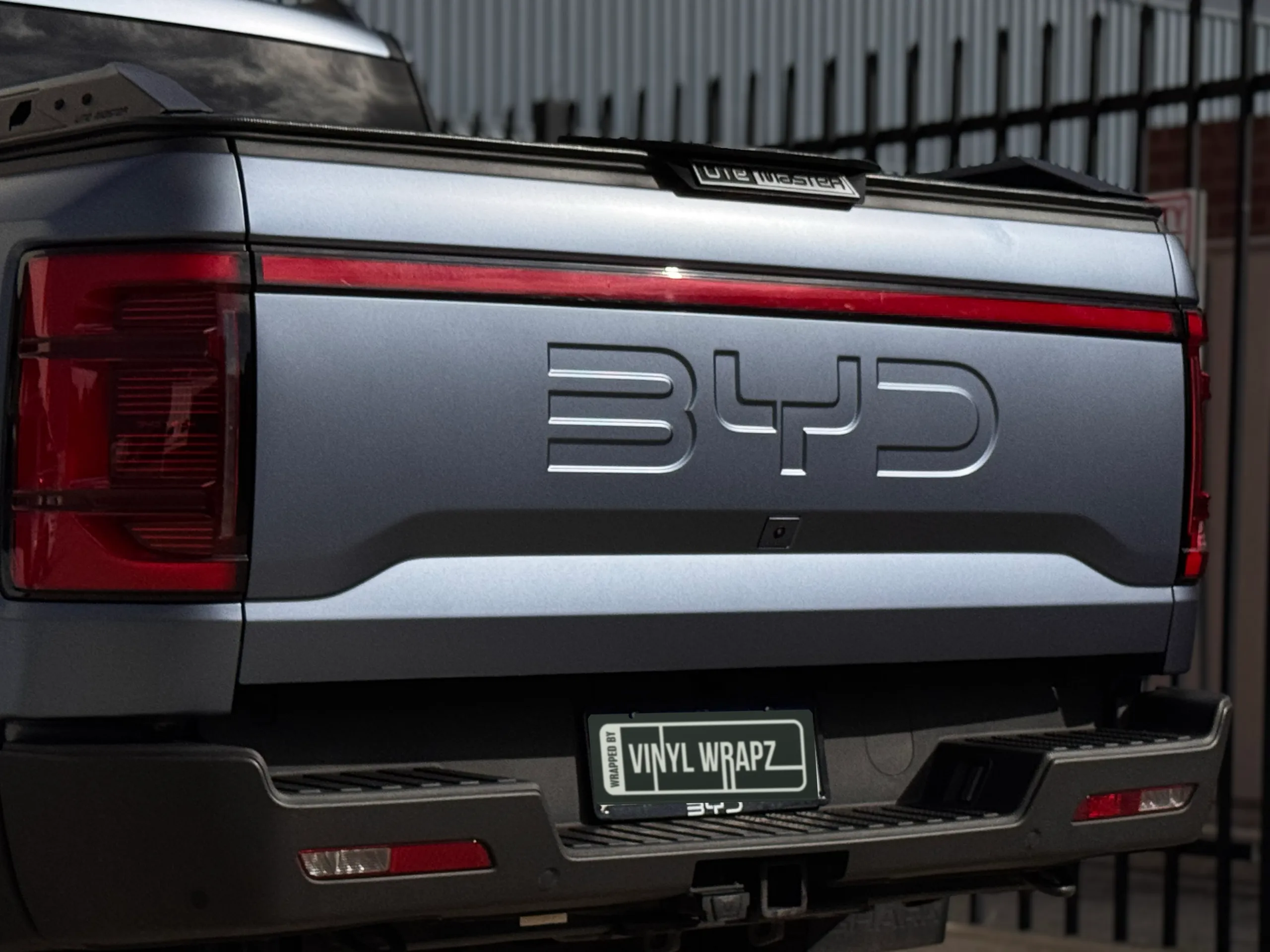 BYD lettering across the matte blue-grey Shark tailgate beneath the red light bar