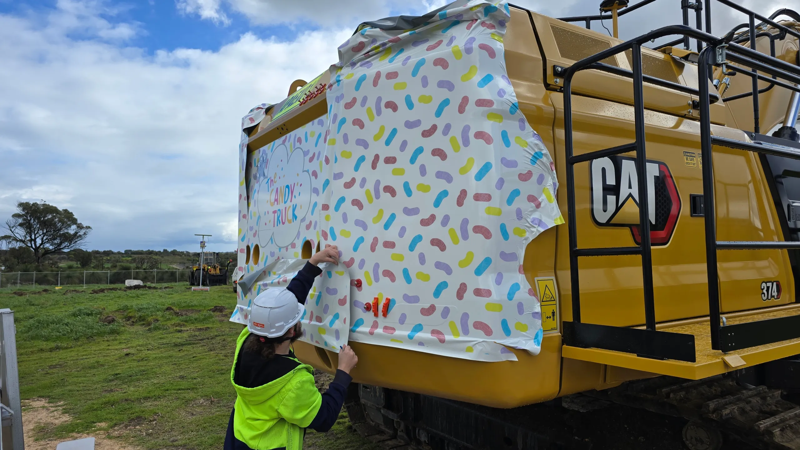 Installer fitting printed graphics to the excavator rear body