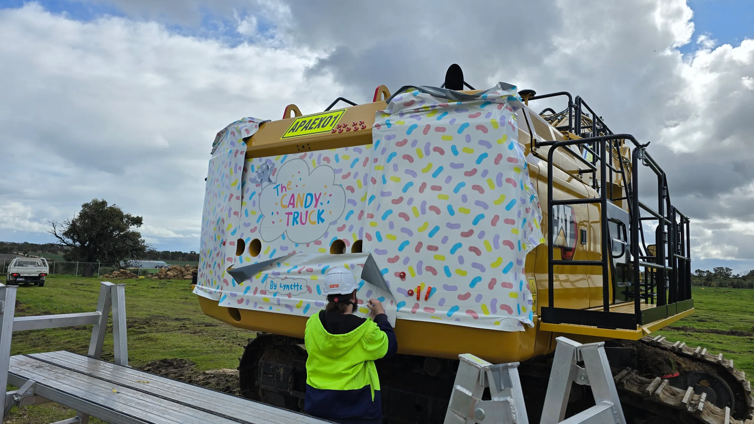 Installer facing the excavator while fitting Candy Truck graphics