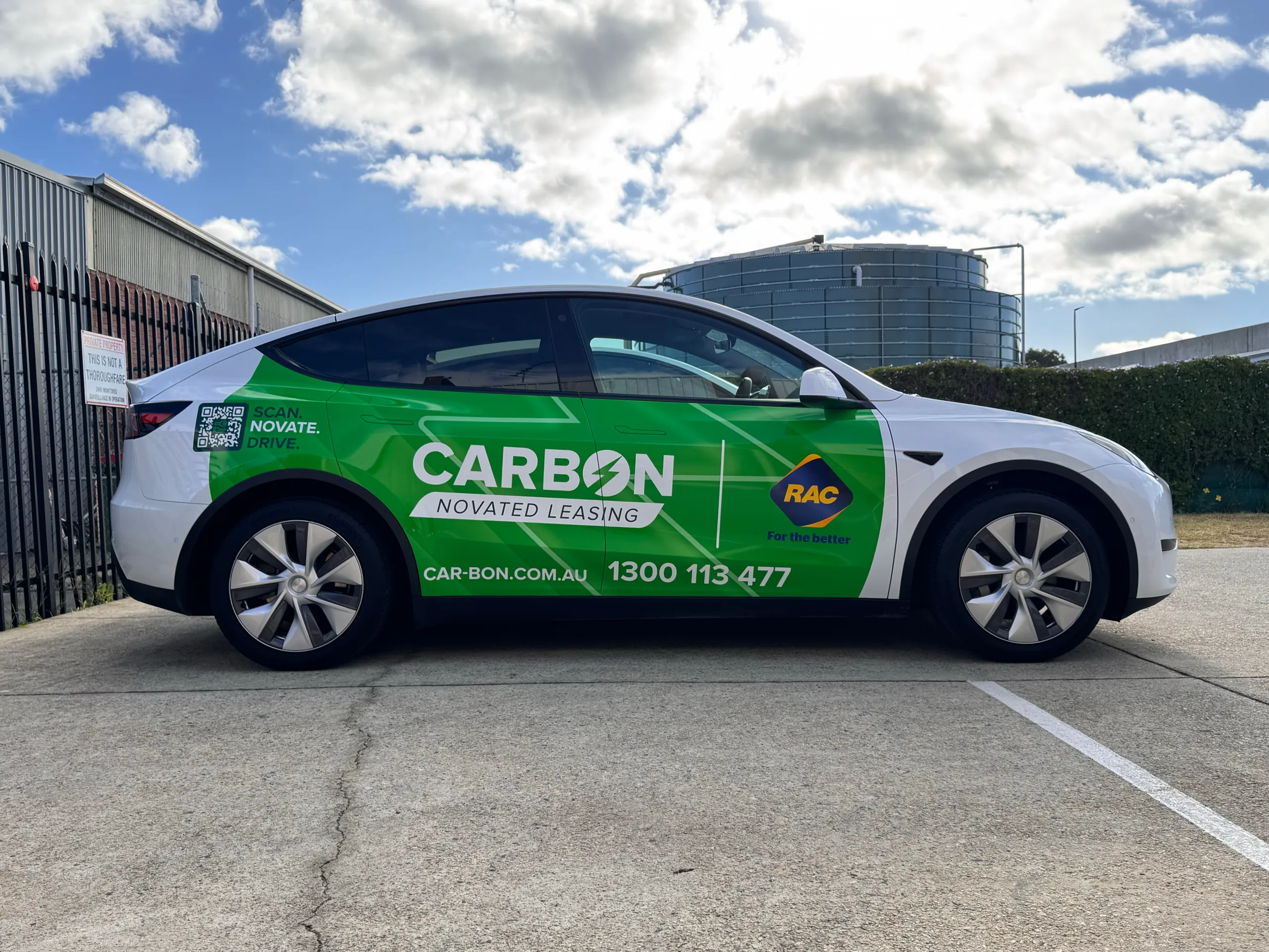 Side view of a white Tesla Model Y with green Carbon and RAC branding