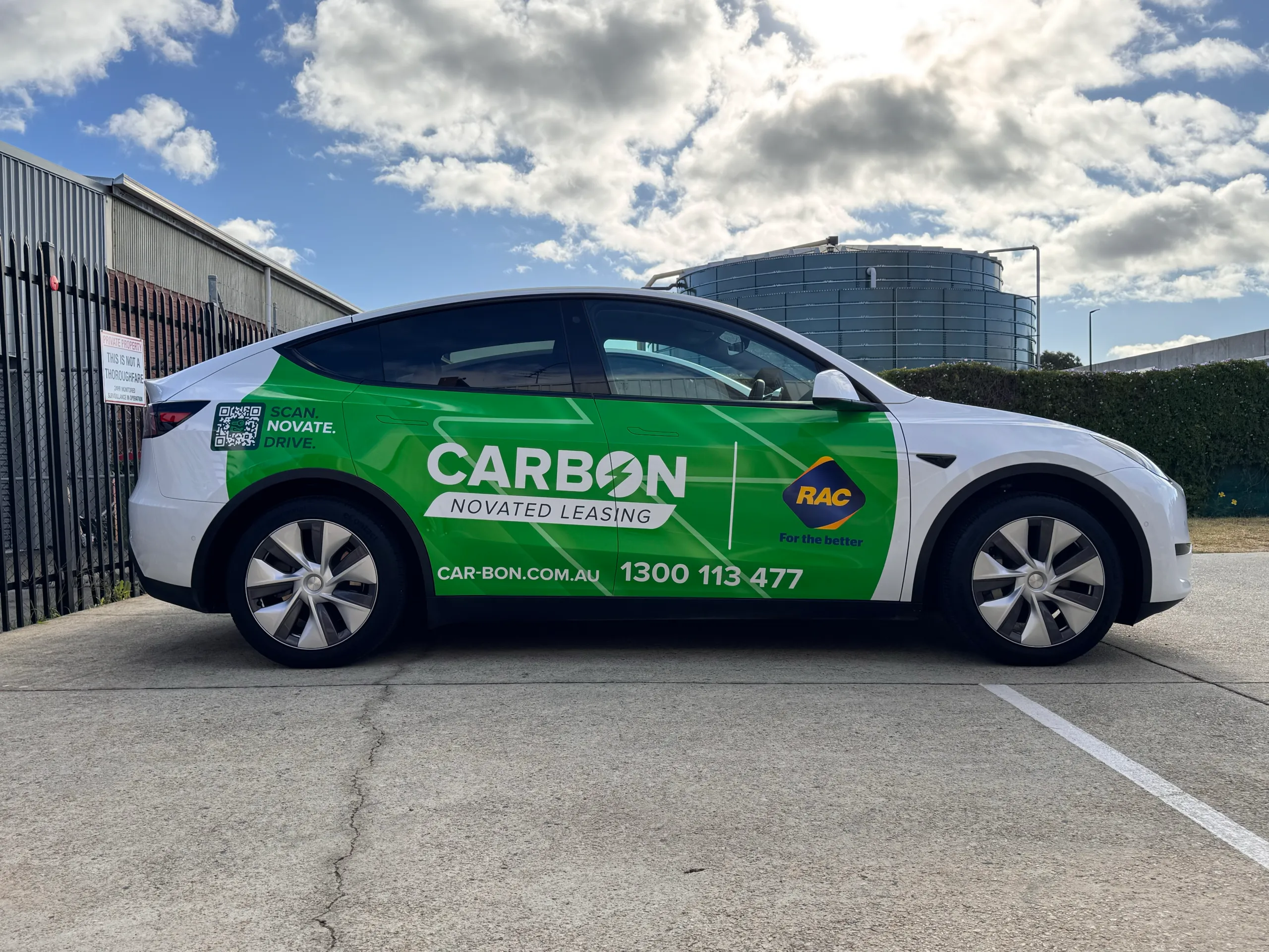 Green Carbon novated leasing graphics across a white Tesla Model Y outside the workshop