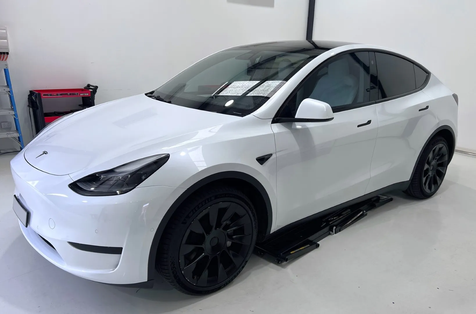 White Tesla Model Y on the hoist at the Vinyl Wrapz workshop