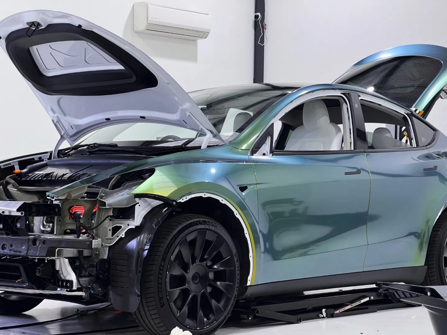 Tesla Model Y mid colour change at Vinyl Wrapz, front bumper and lights removed so the film runs into the panel edges