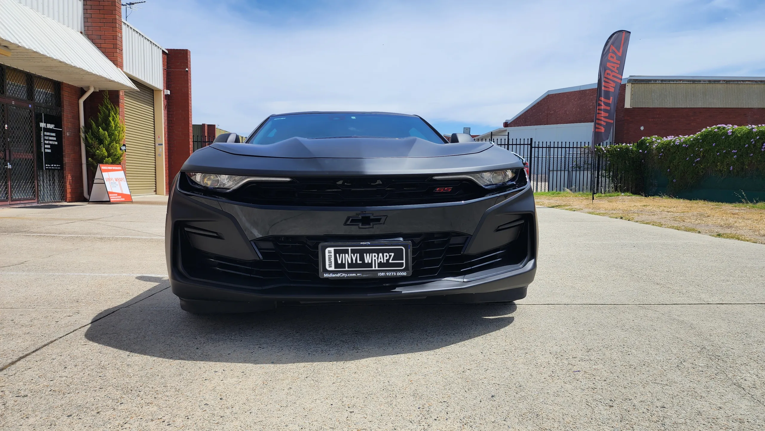 Head-on view of the matte black Chevrolet Camaro SS outside the workshop