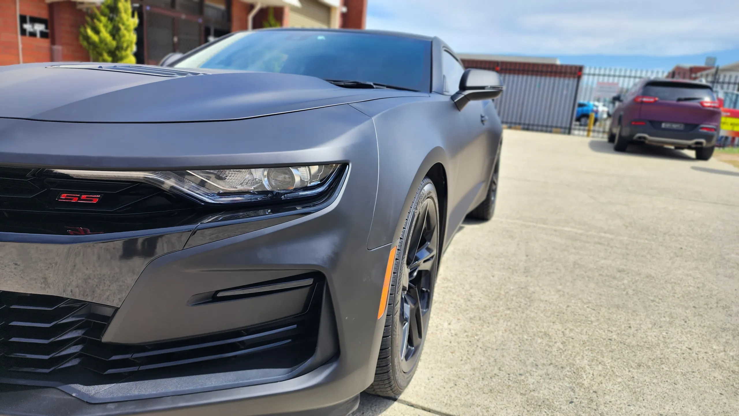 Matte Camaro SS front corner showing its grille badge, headlight and bumper