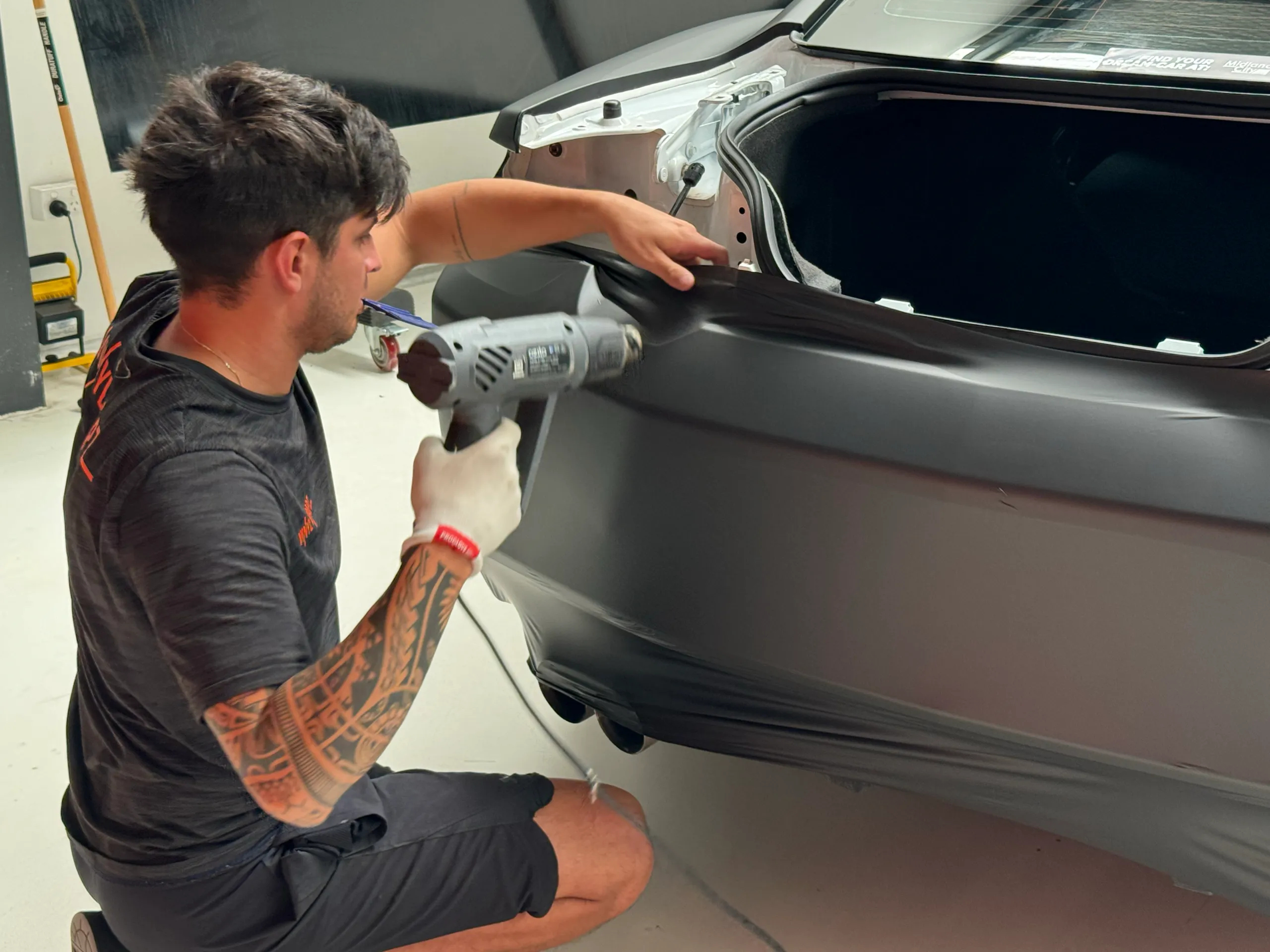 Installer heating dark film on the removed Camaro rear bumper
