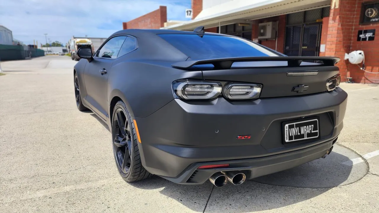 Matte black Chevrolet Camaro rear quarter showing the spoiler and twin exhausts