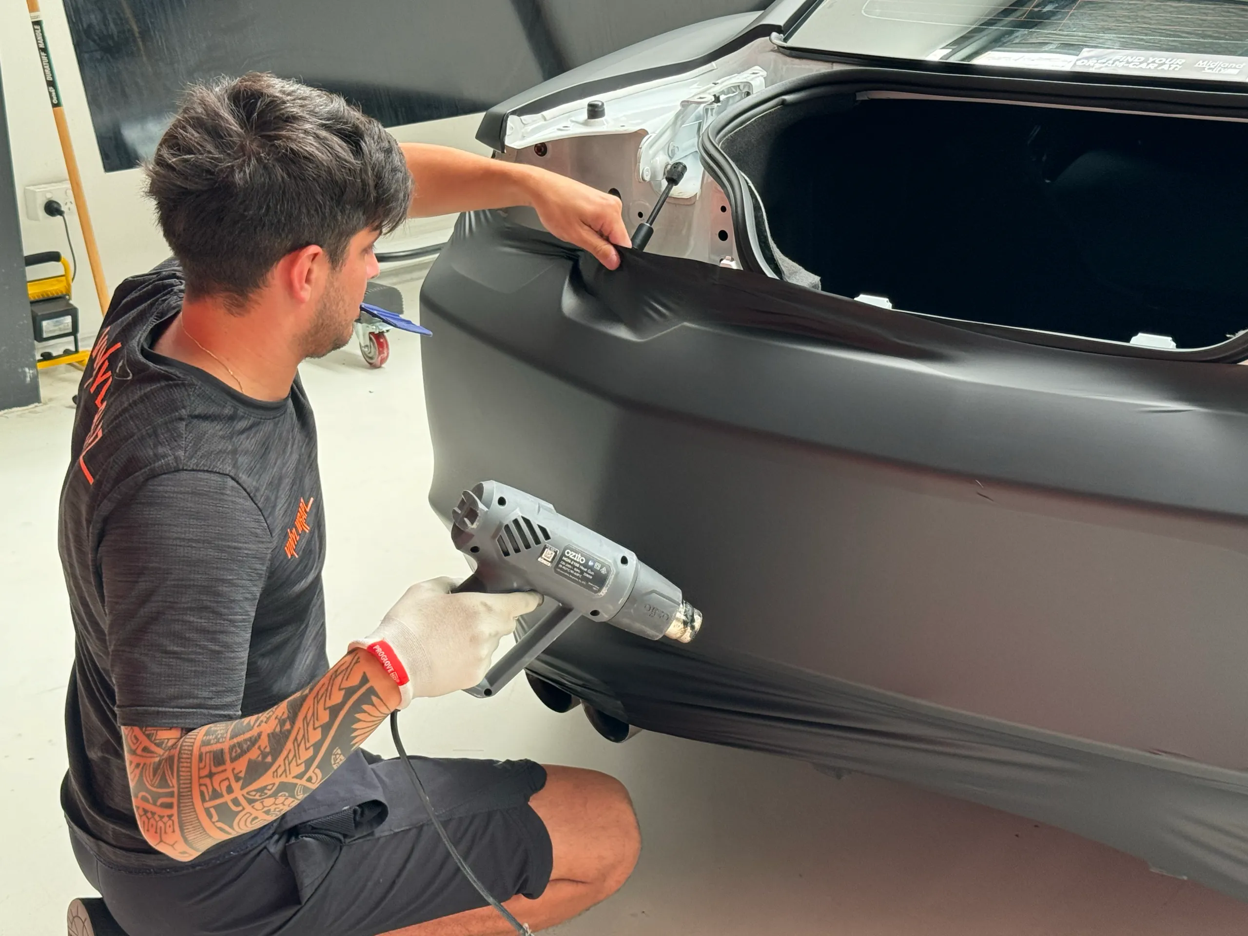 Installer heating matte black film around the Chevrolet Camaro rear quarter