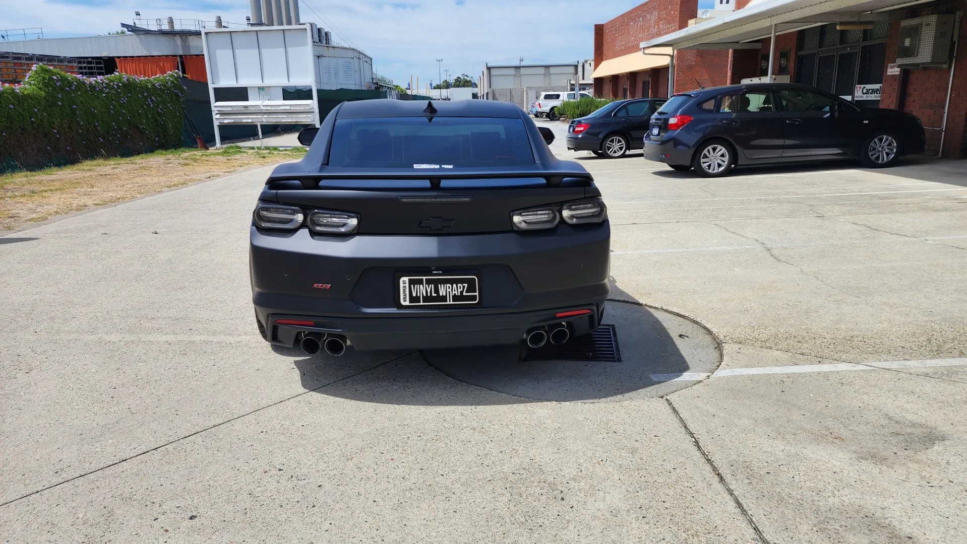 Matte black Chevrolet Camaro rear view outside the workshop