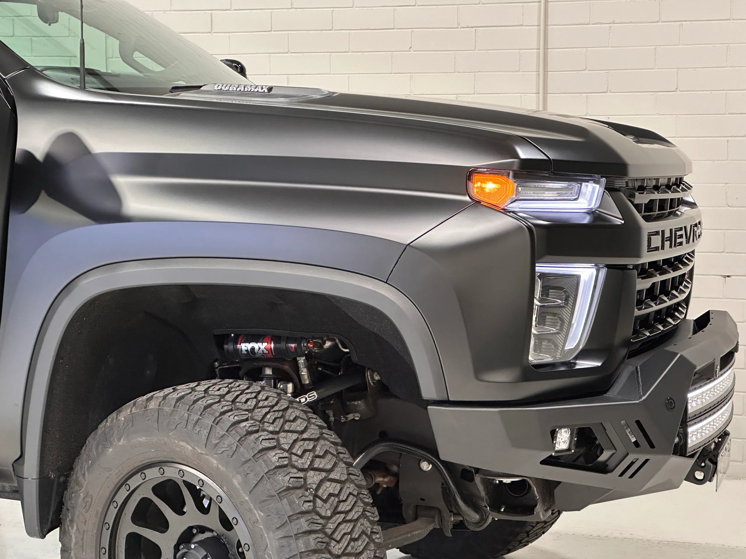 Chevrolet Silverado front guard, bonnet and headlight in matte black, above a large off-road tyre