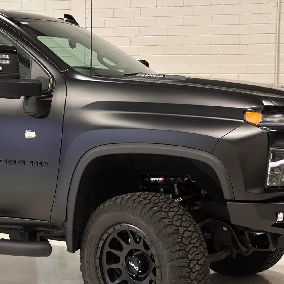 Matte black Chevrolet Silverado 2500 HD front door and guard, showing its badge and large front wheel