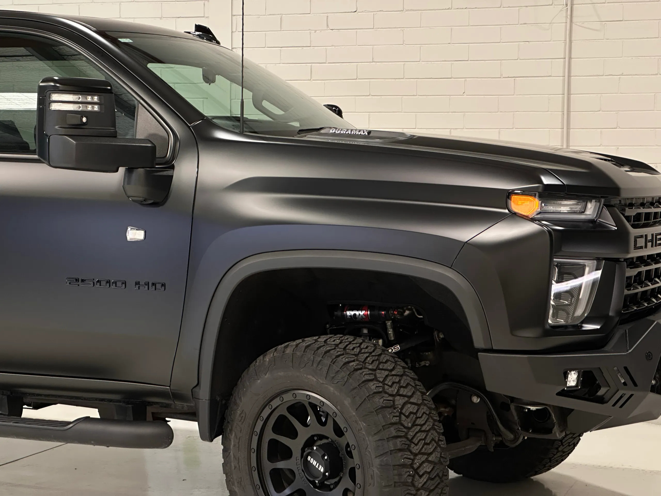 Matte black Chevrolet Silverado 2500 HD front door and guard, showing its badge and large front wheel