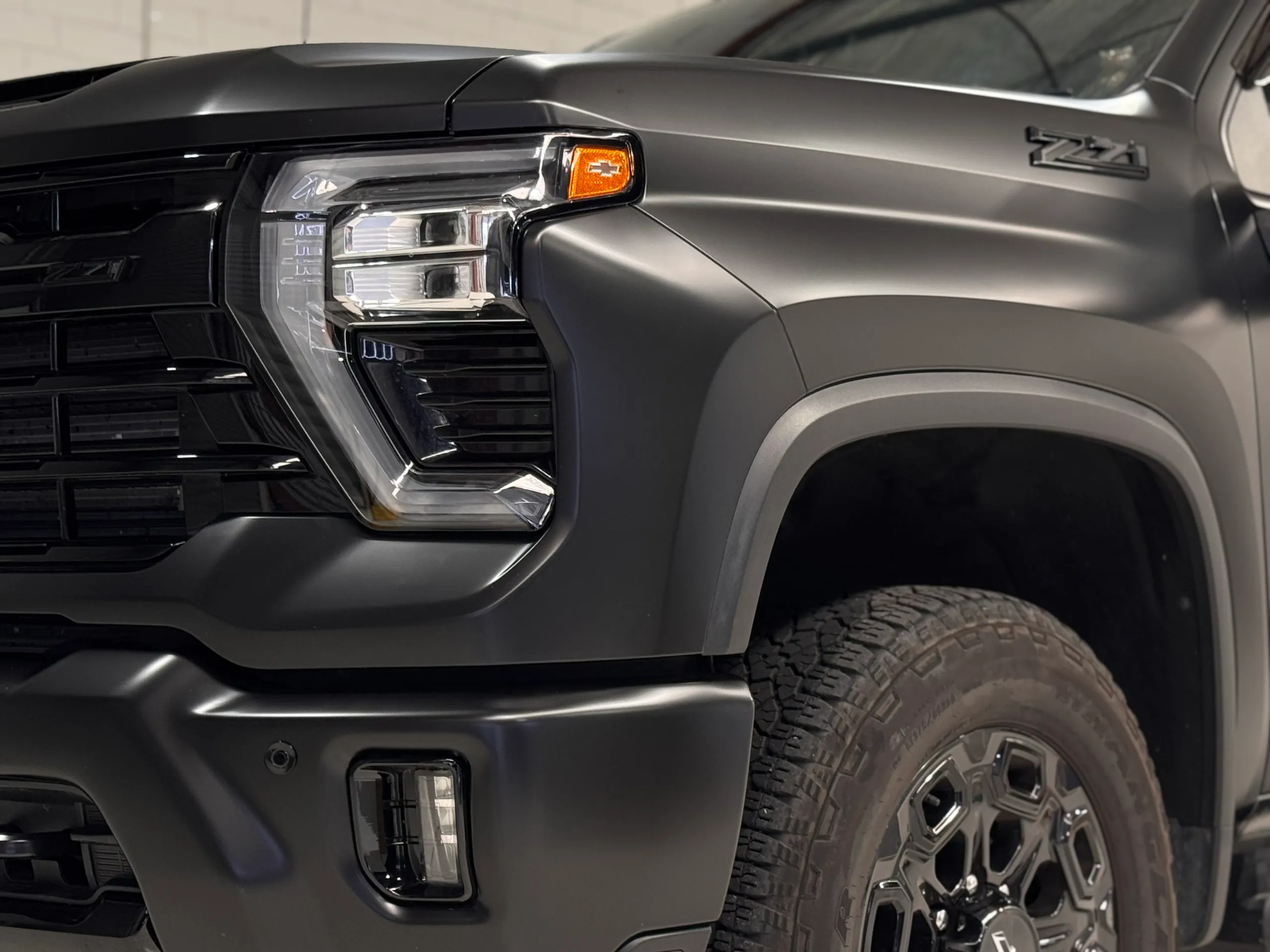 Low close view of the matte grey Silverado headlight and front wheel arch