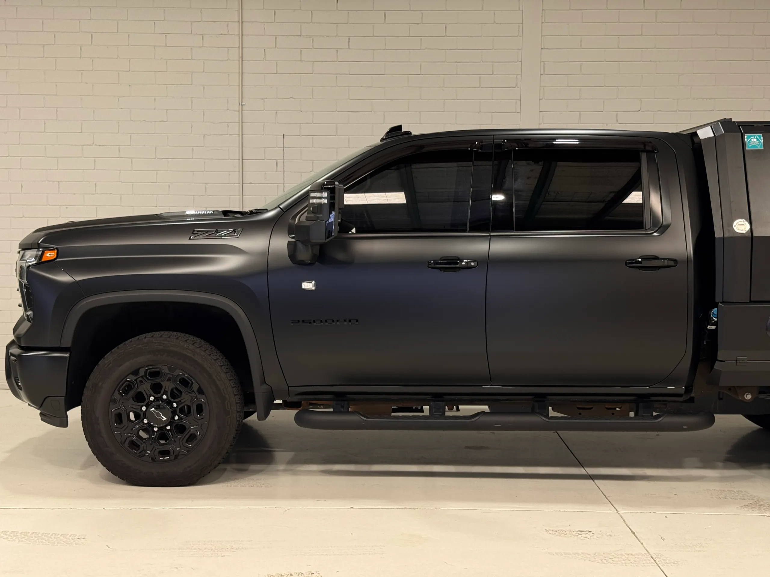 Closer side view of the matte grey Silverado cab and front wheel
