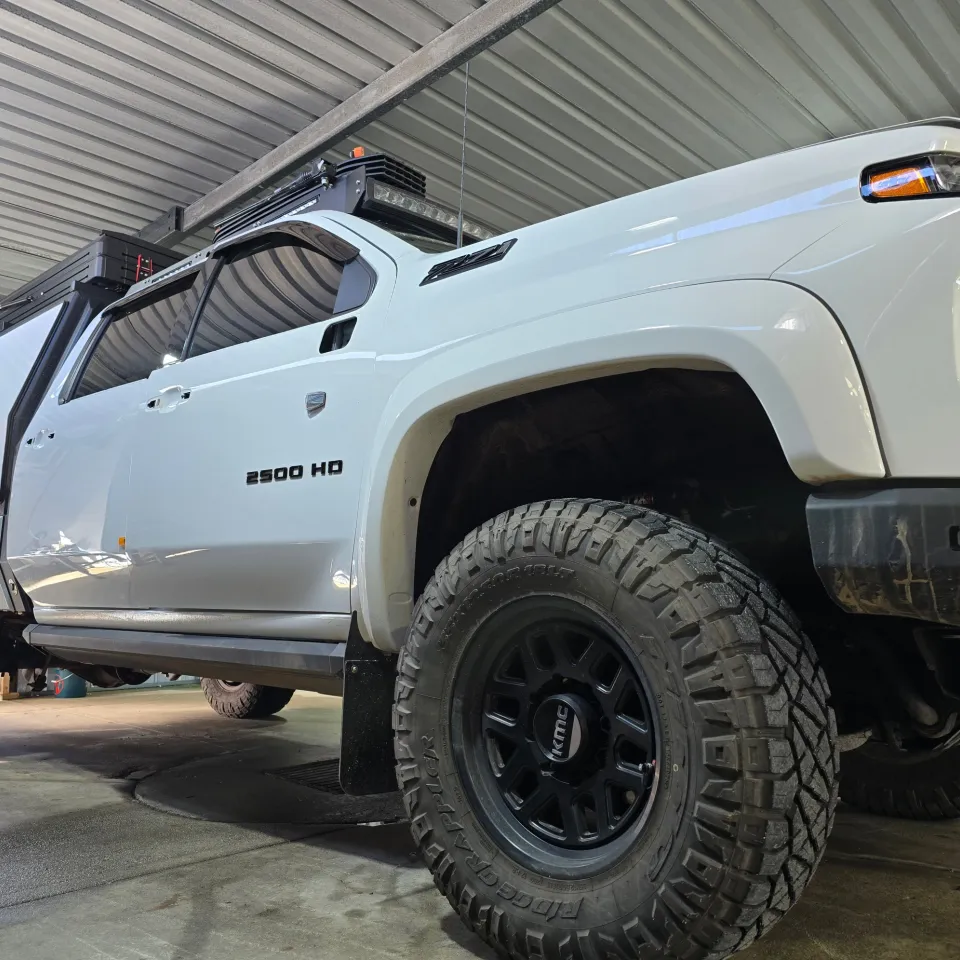 Low view of a white Chevrolet Silverado 2500 HD with a canopy inside the workshop