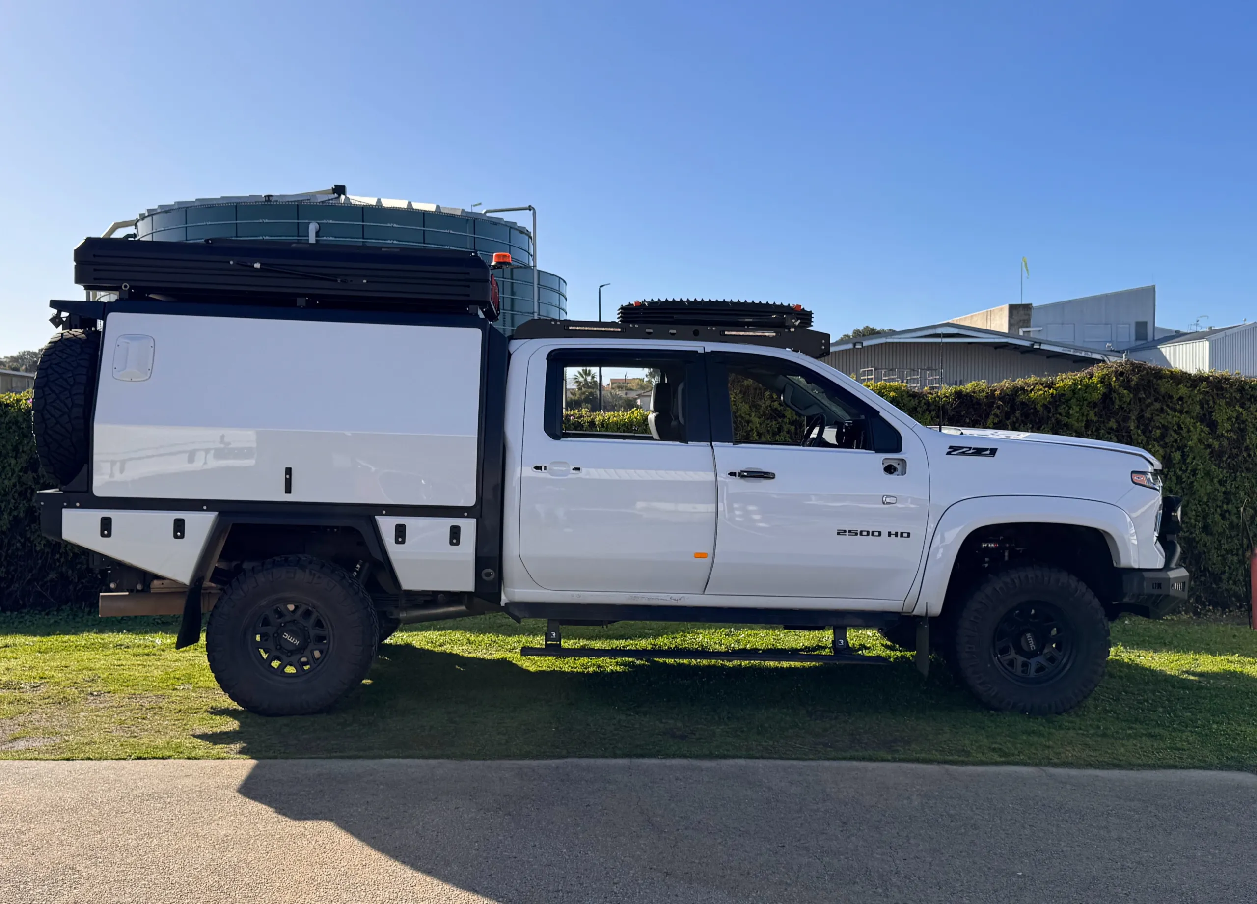 Side profile of the white Silverado 2500 HD and its touring canopy outdoors