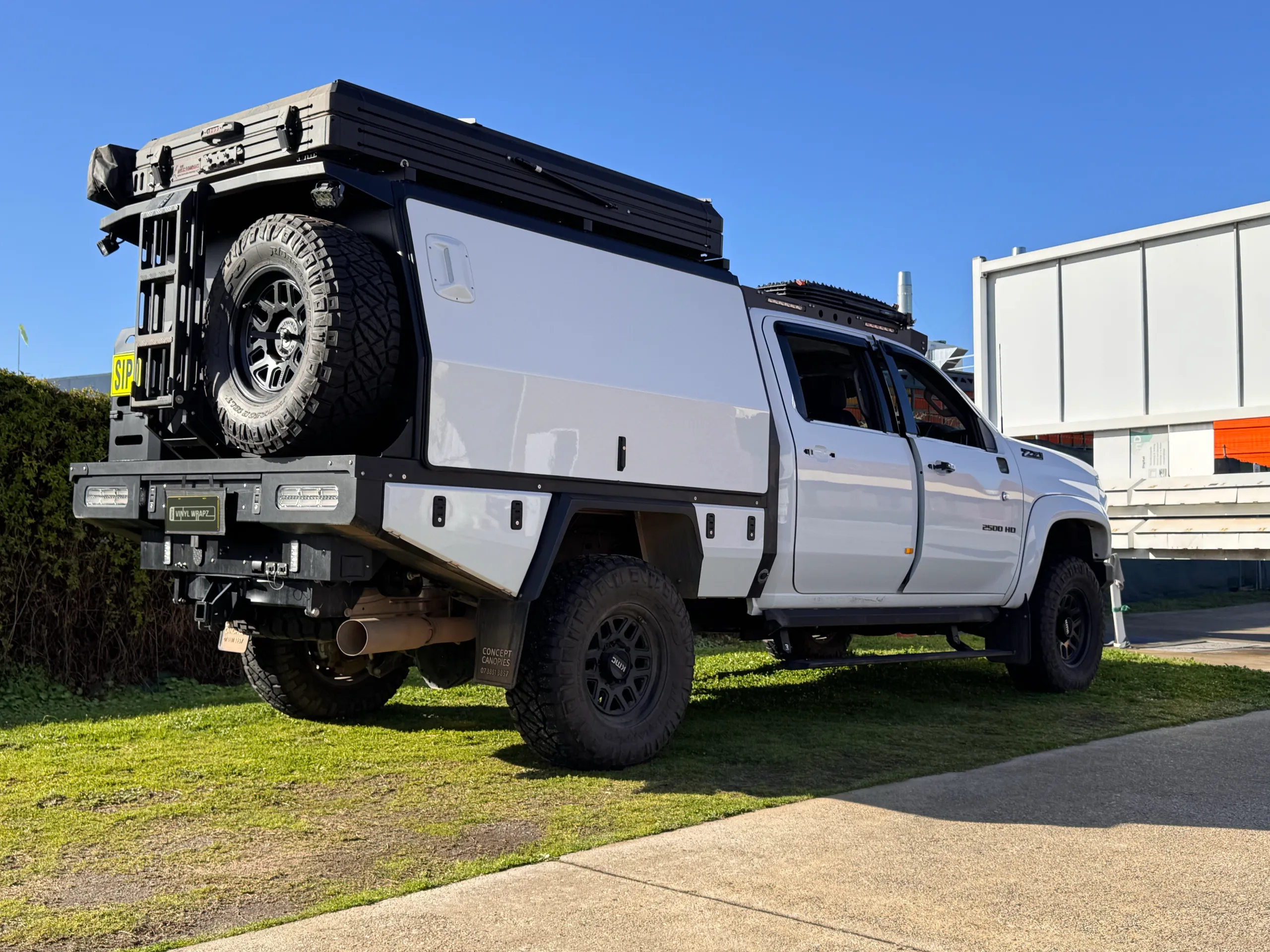 Rear-quarter view of the white Silverado 2500 HD with a canopy-mounted spare wheel