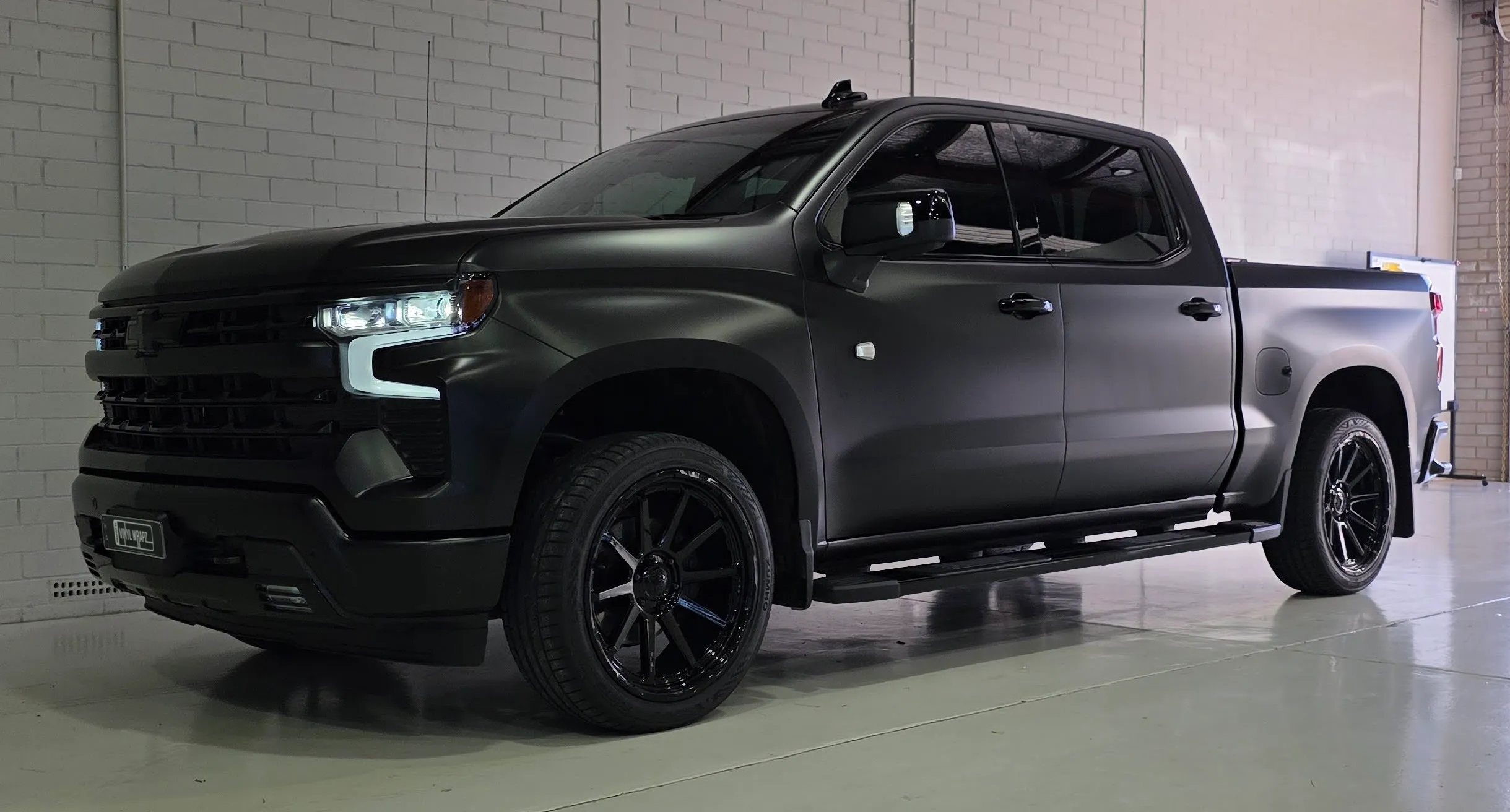 Satin black Chevrolet Silverado with black wheels and running boards in the workshop