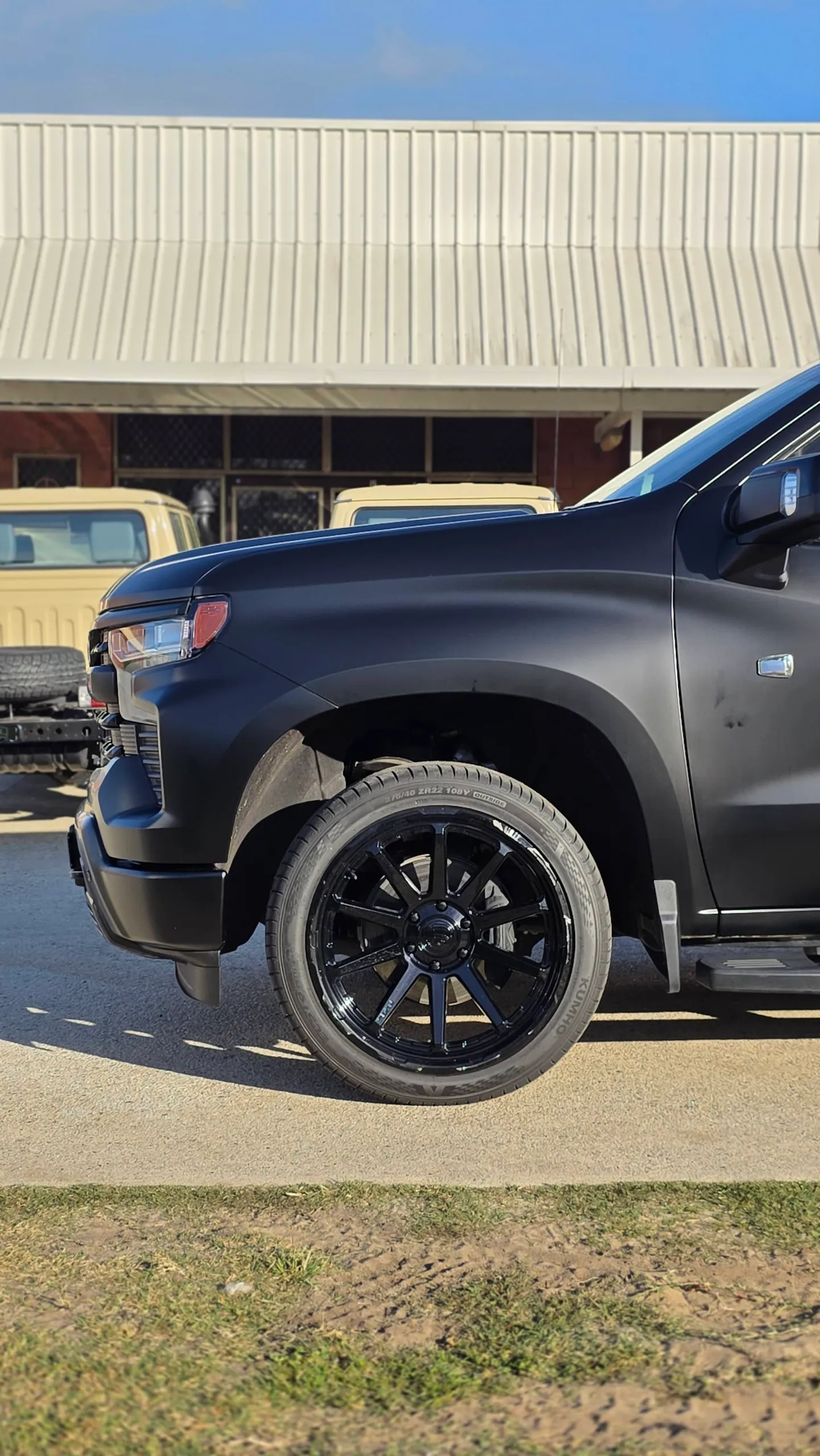 Black front wheel beneath the satin black Chevrolet Silverado guard
