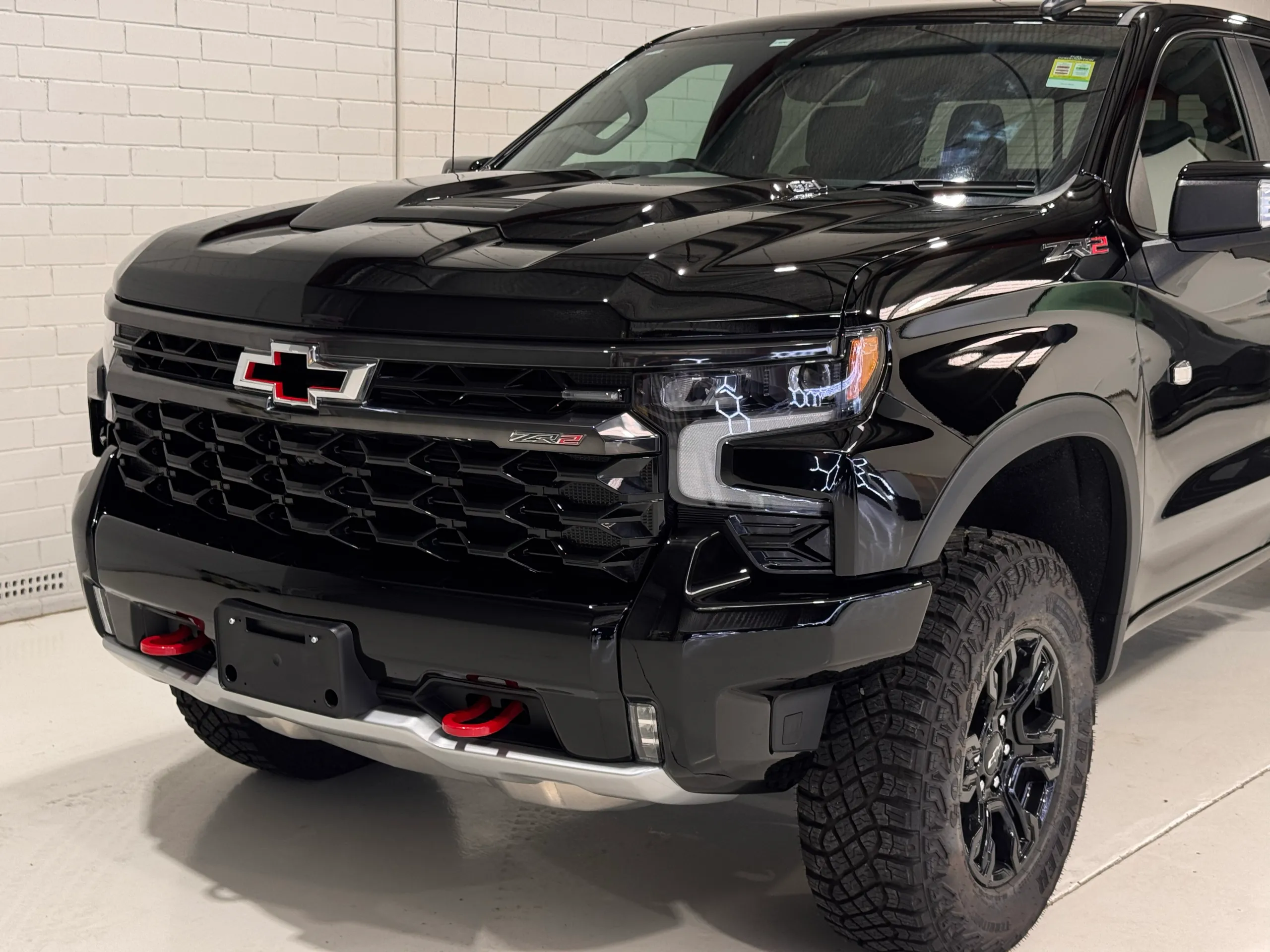Gloss black Chevrolet Silverado ZR2 grille, red tow hooks and front wheel in the workshop