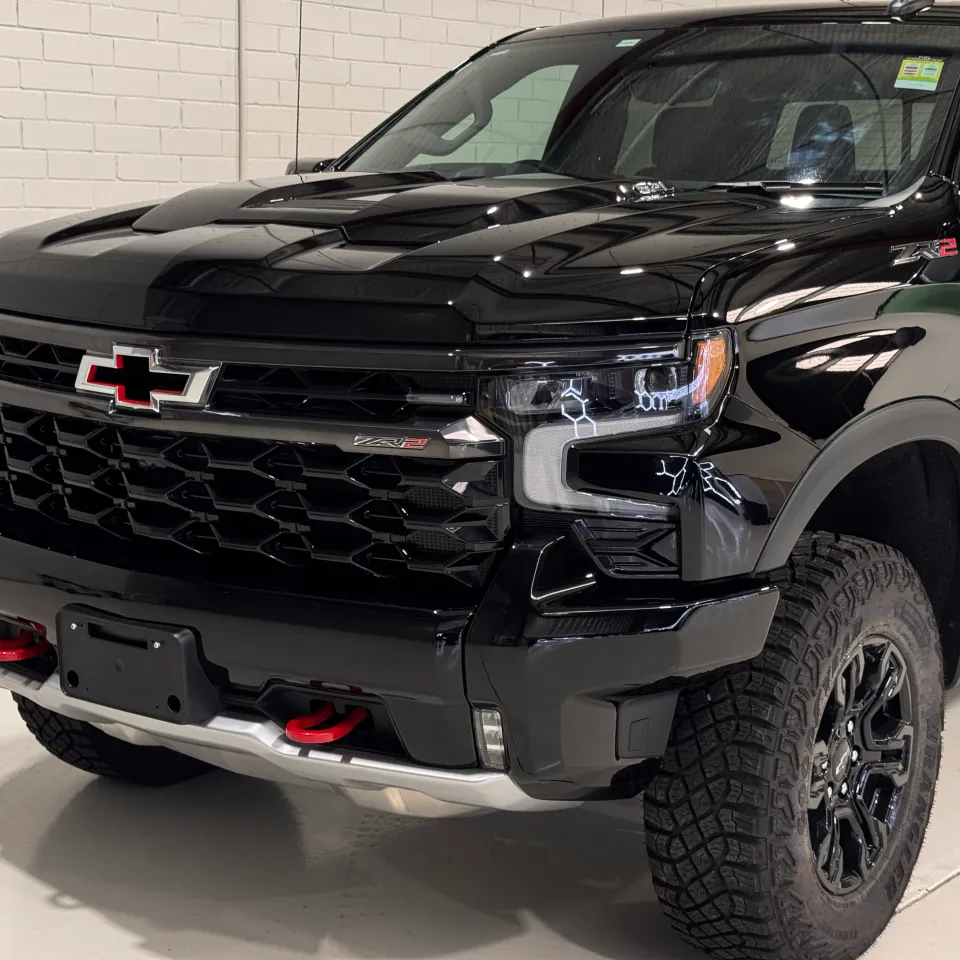 Gloss black Chevrolet Silverado ZR2 grille, red tow hooks and front wheel in the workshop