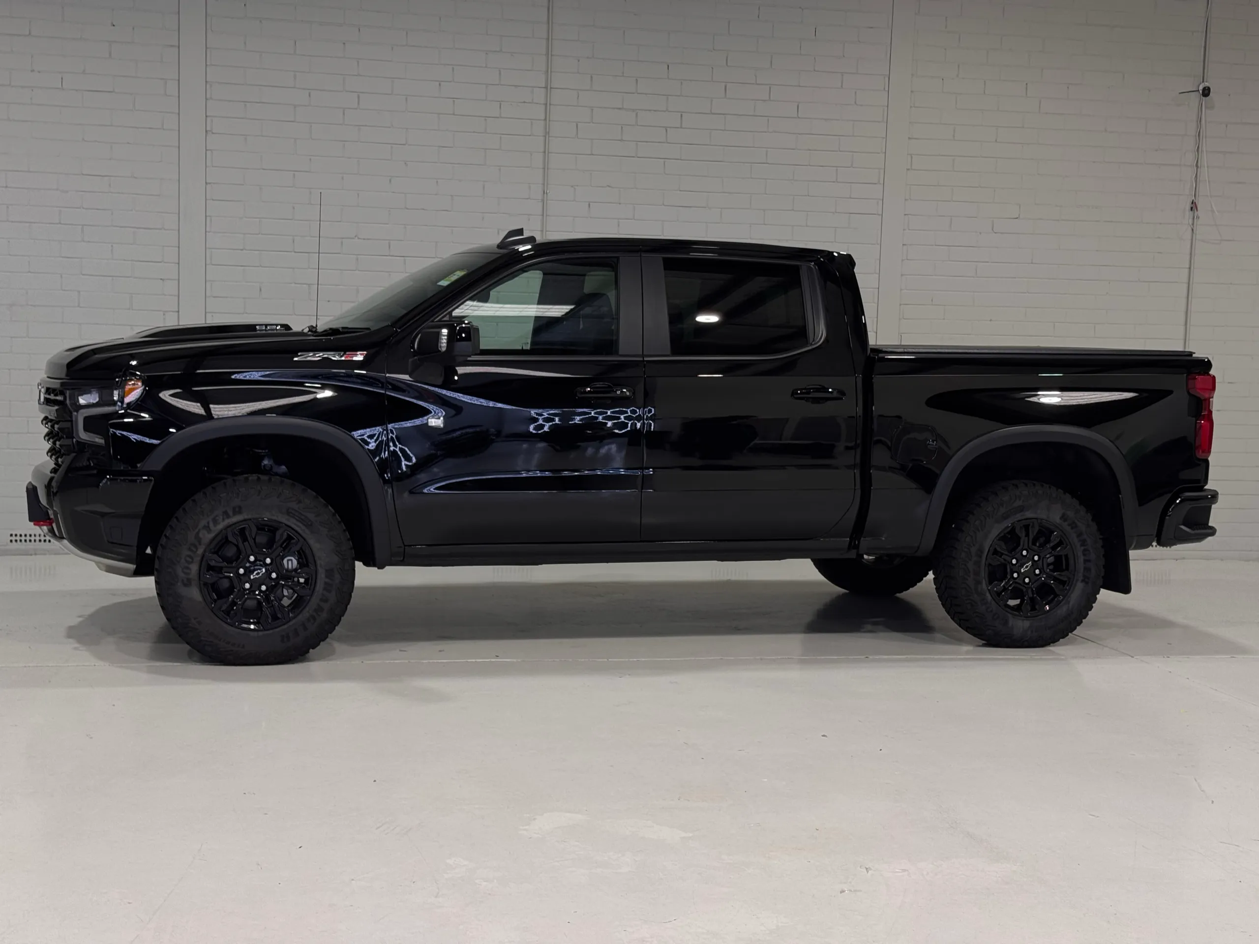 Side view of the gloss black Chevrolet Silverado ZR2 against a white workshop wall