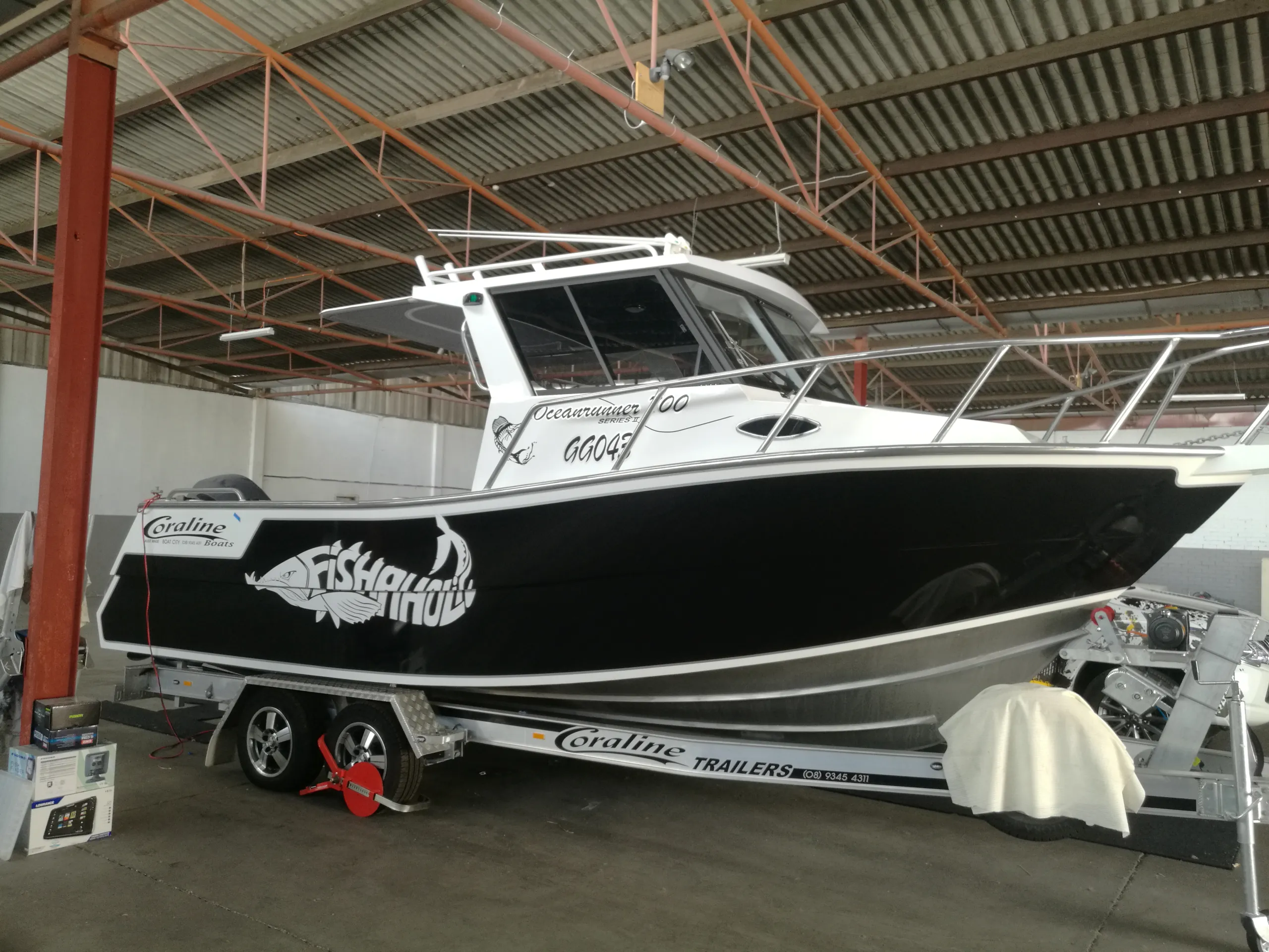 Coraline fishing boat on its trailer with a glossy black hull and white Fishaholic graphics
