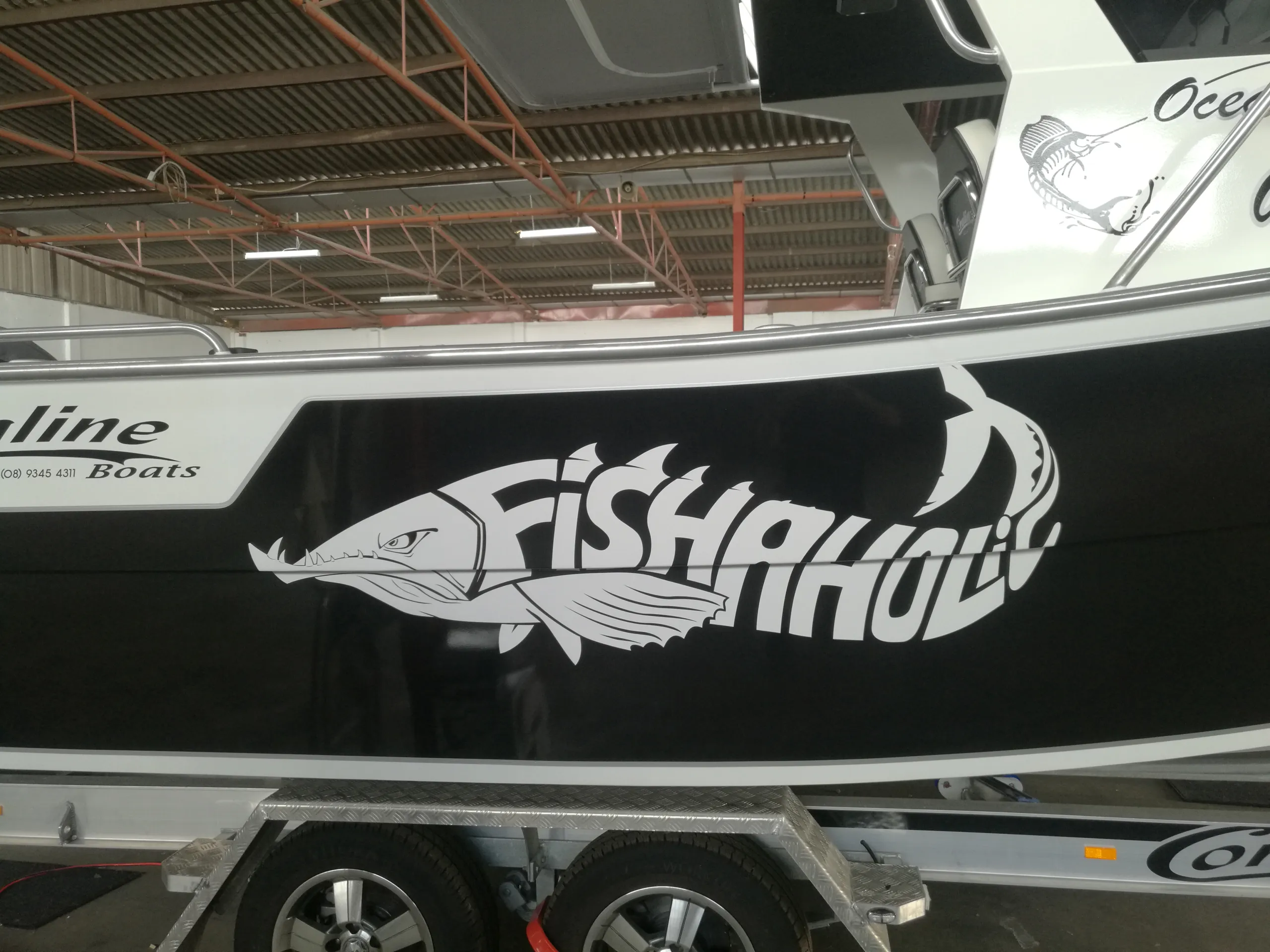 Close-up of the white Fishaholic fish graphic on a black Coraline boat hull