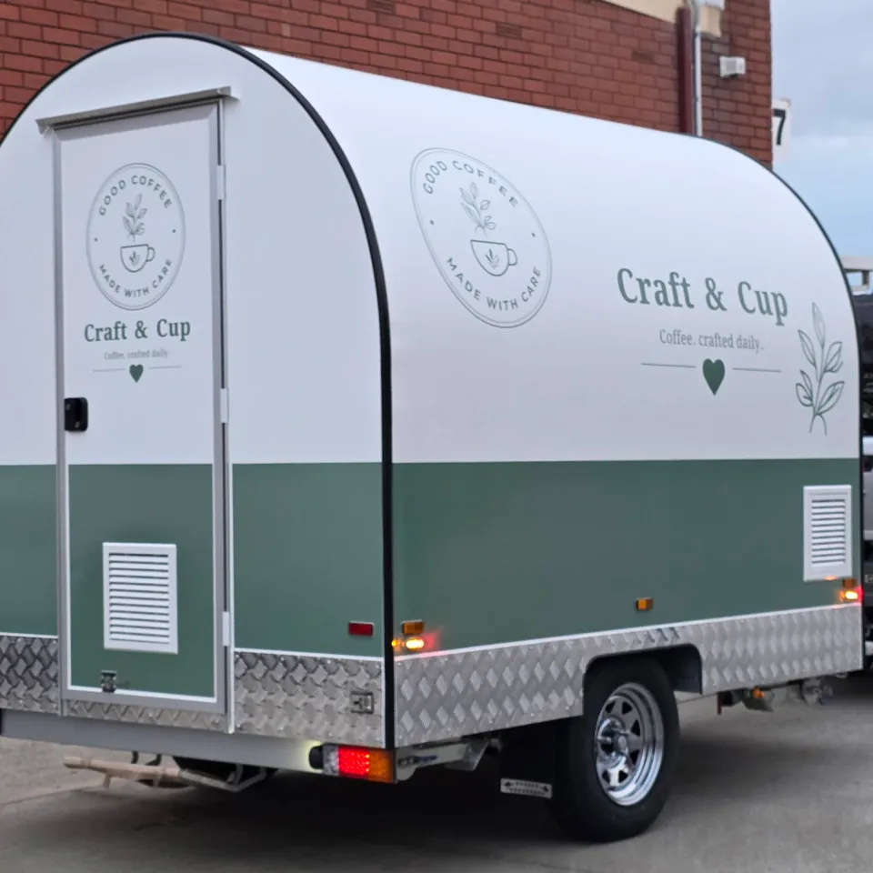 White and sage green Craft & Cup coffee trailer with branding on its side and rear door