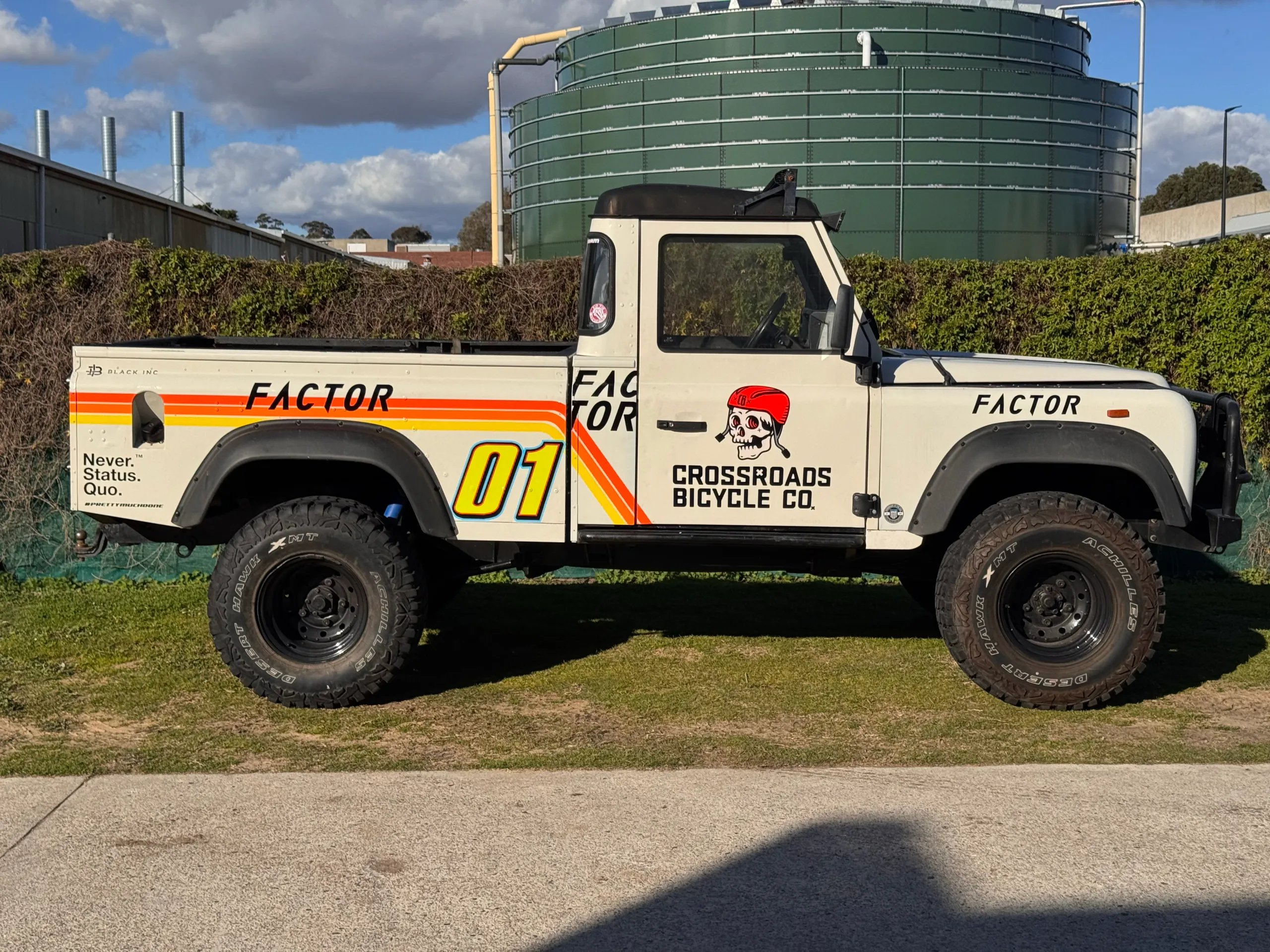 Side profile of the cream Land Rover Defender ute with Crossroads Bicycle Co and Factor graphics