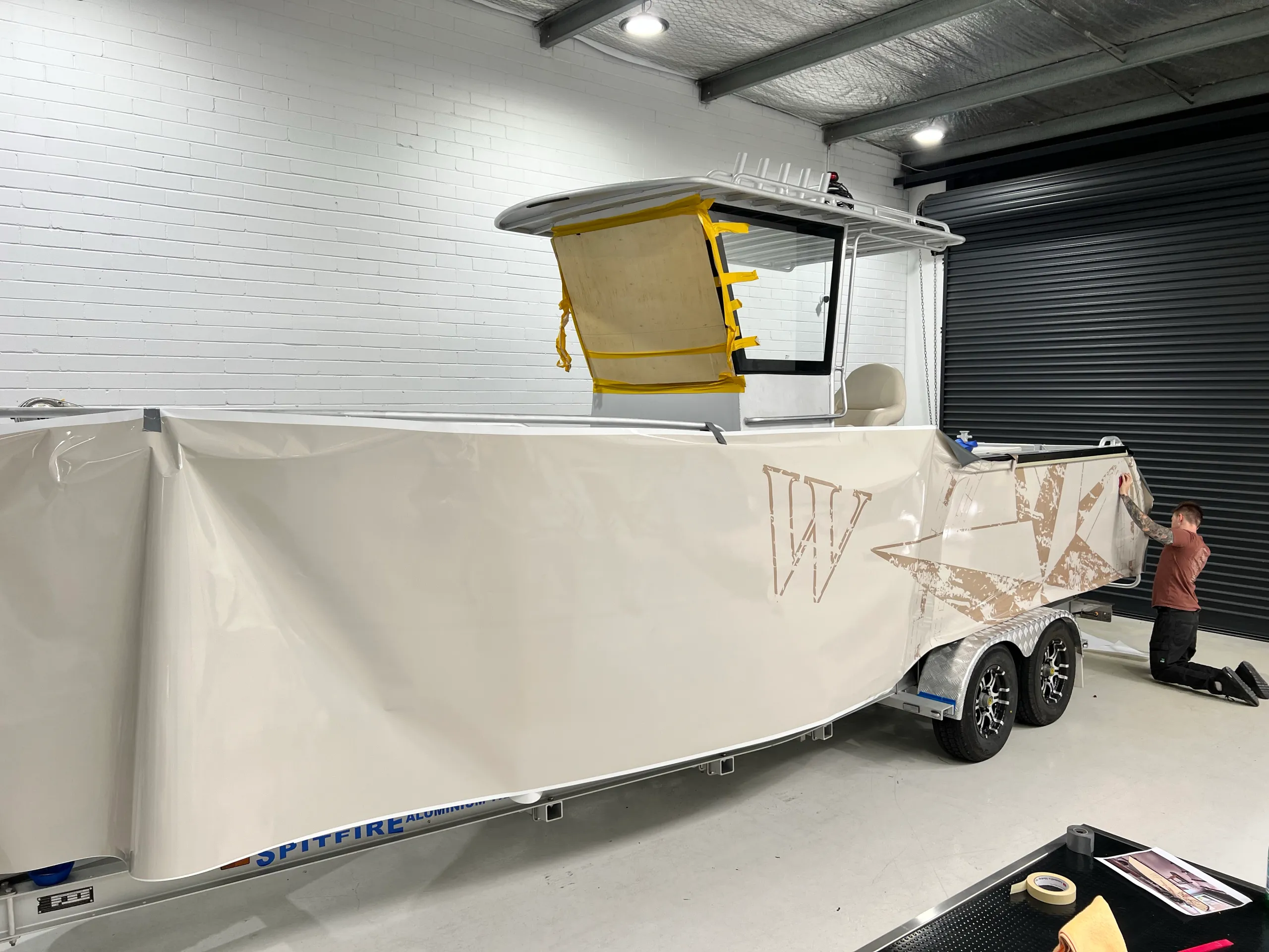 Cream film with compass artwork being fitted along the boat hull