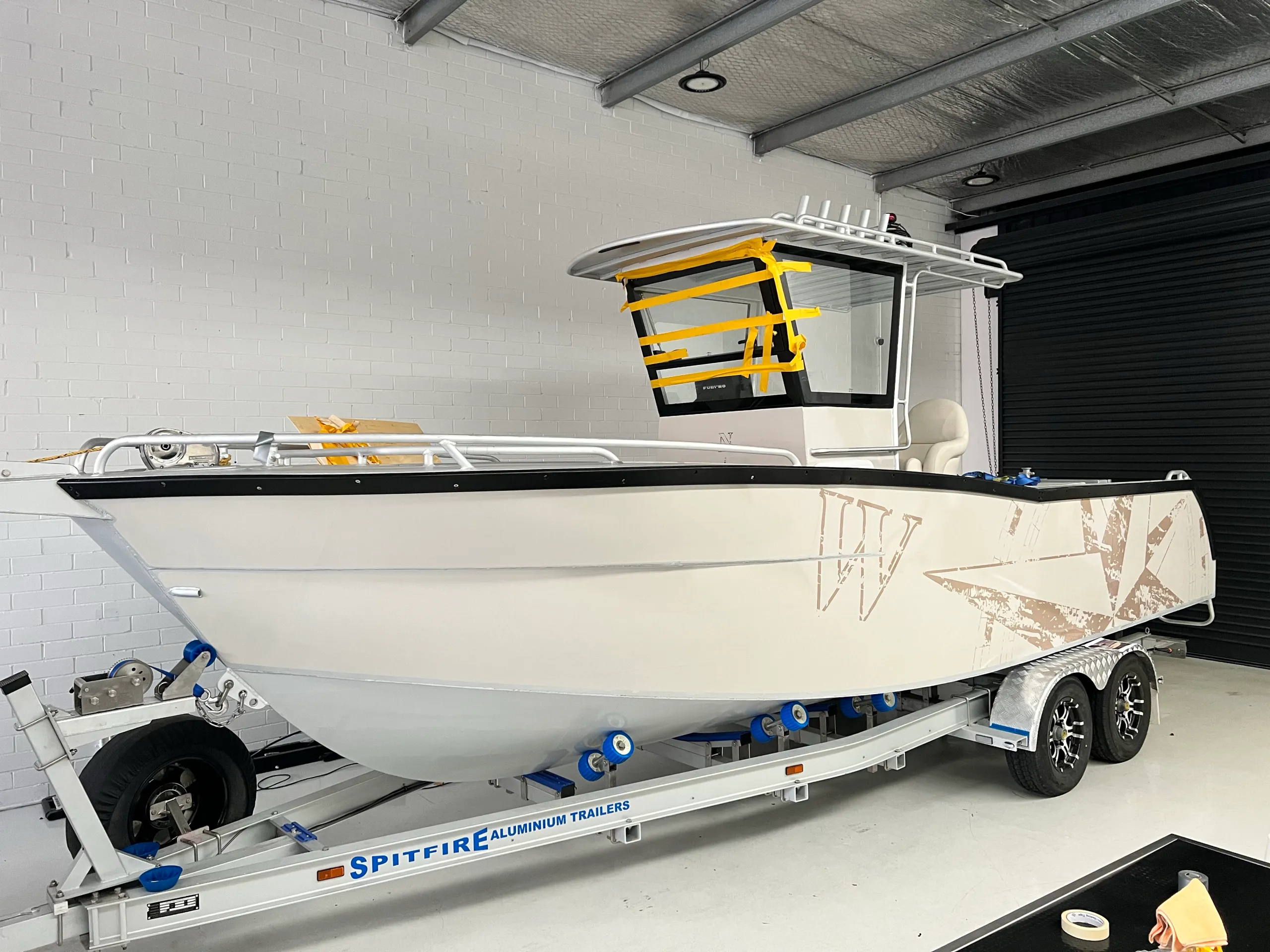 Cream and brown compass graphics fitted to the boat hull with its windscreen still masked