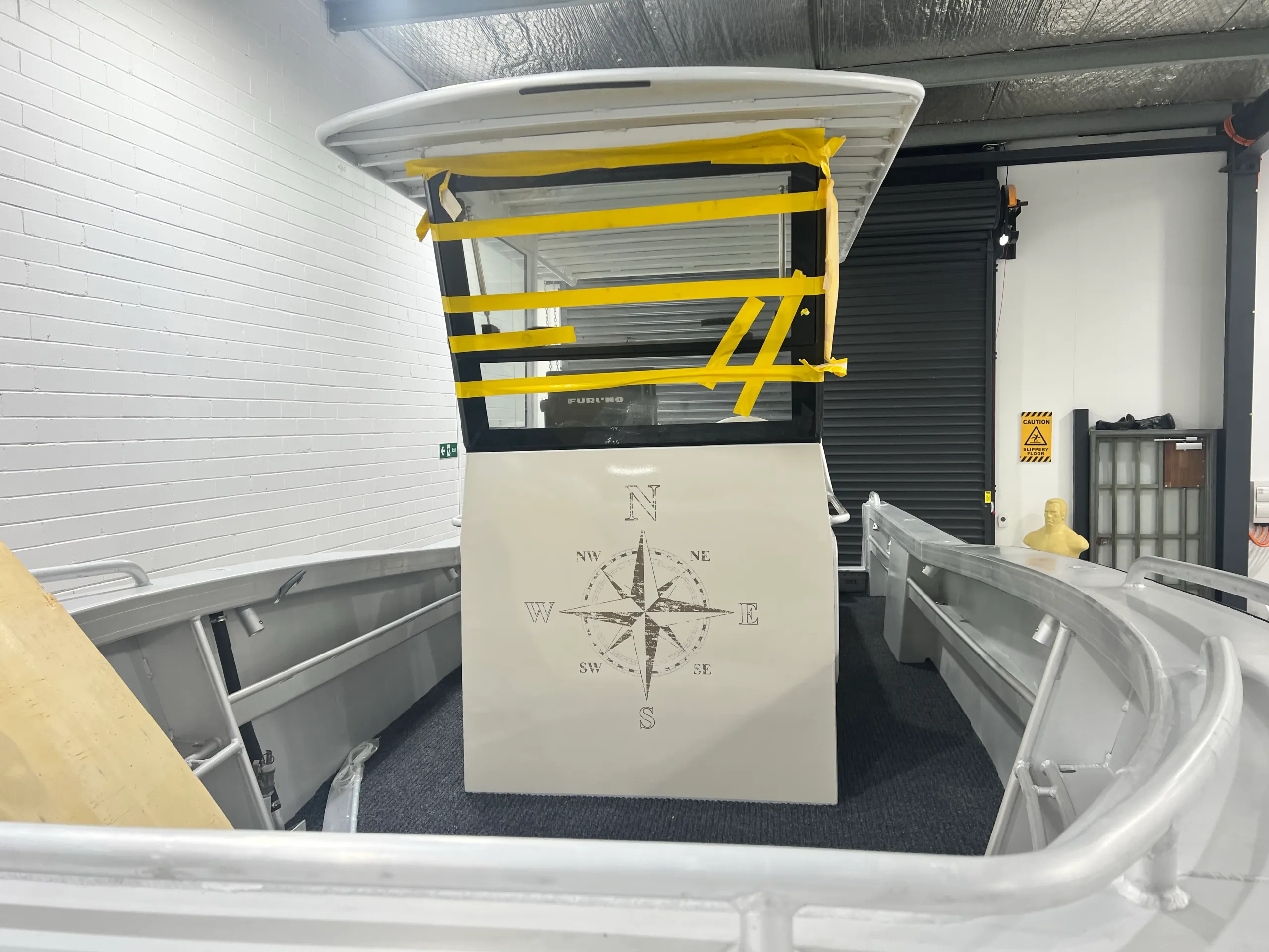 Compass artwork on the boat console beneath a windscreen covered with masking tape