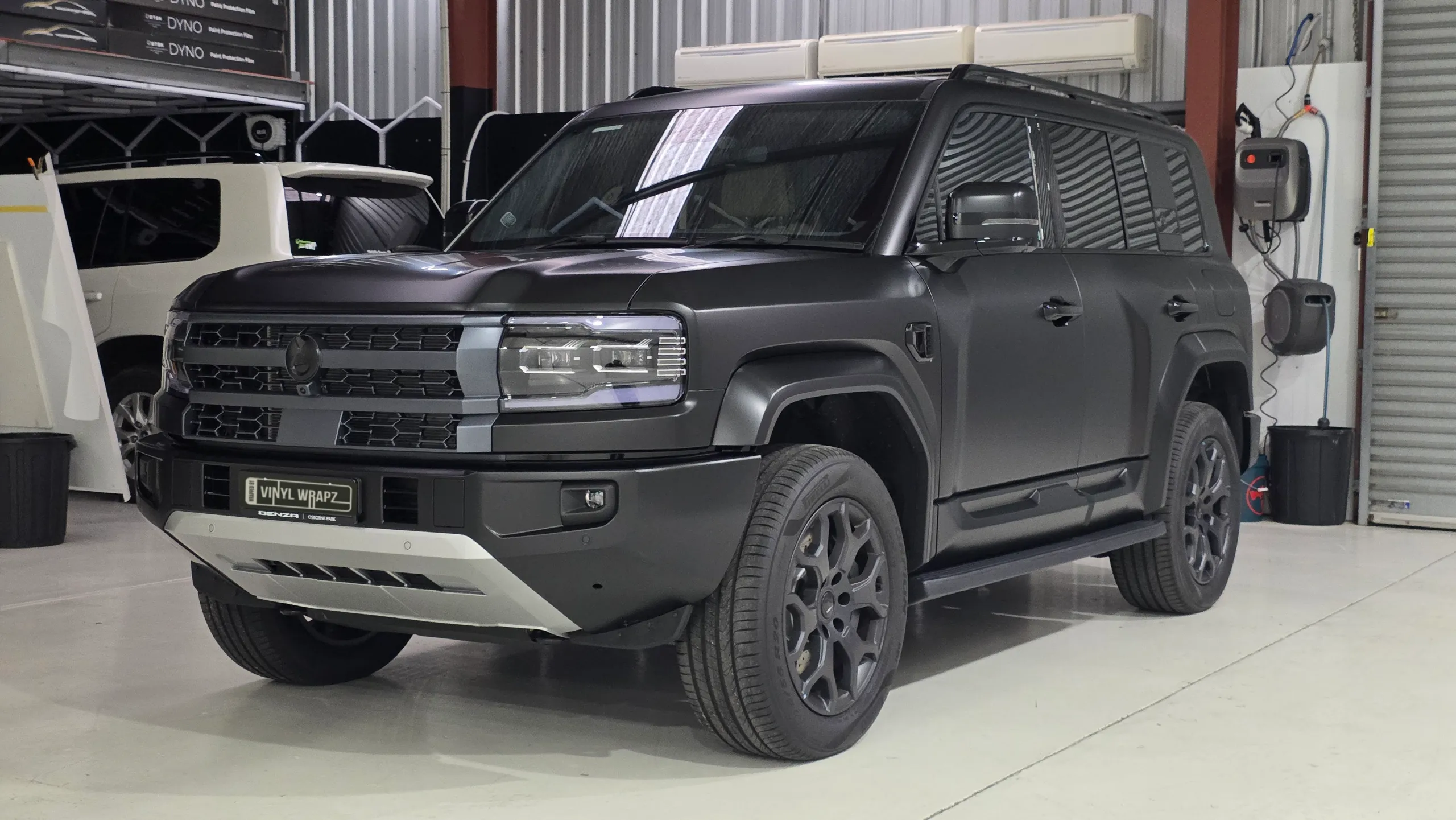 Satin dark grey Denza B5 viewed from the front quarter in the workshop