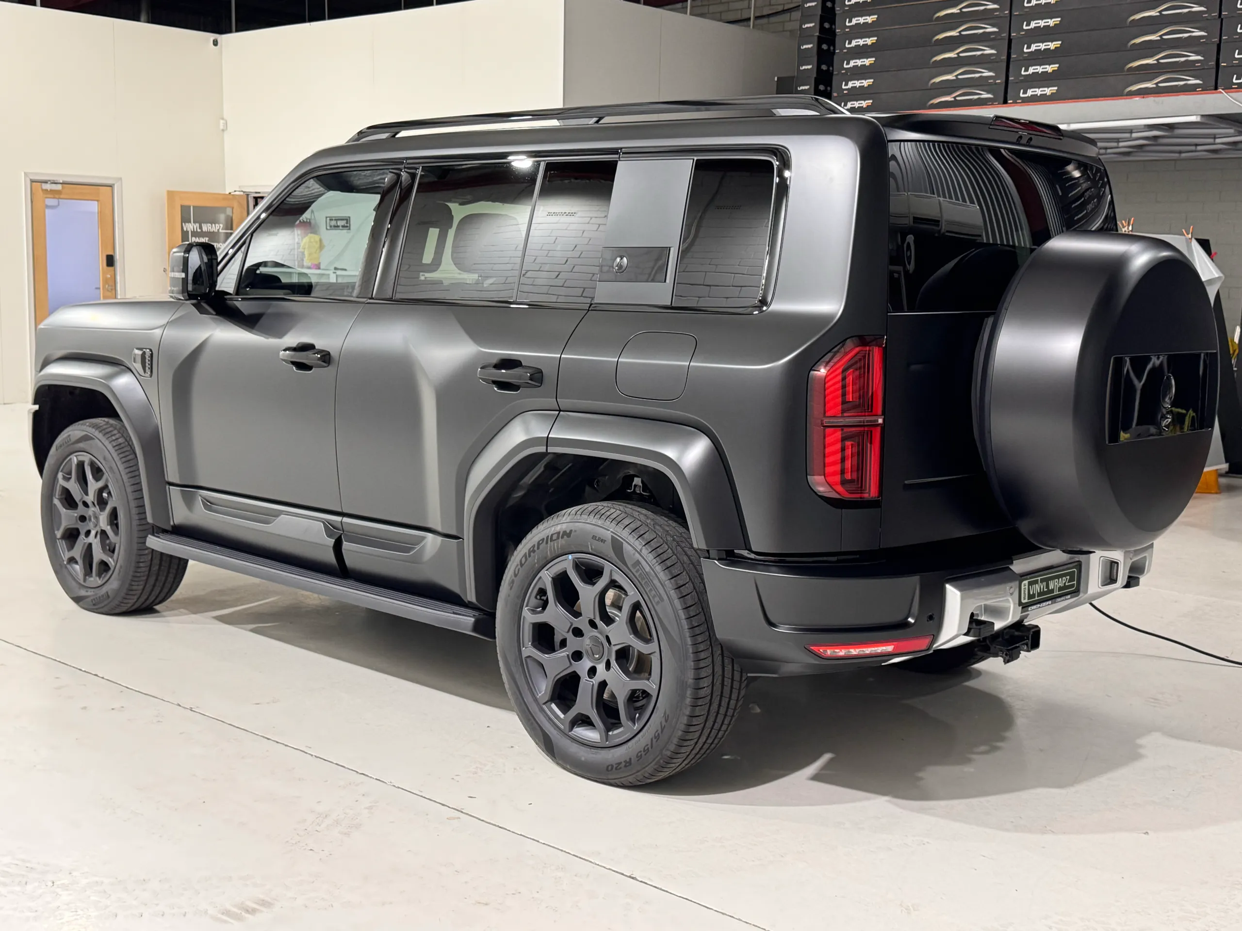 Satin dark grey Denza B5 viewed from the rear quarter inside the workshop